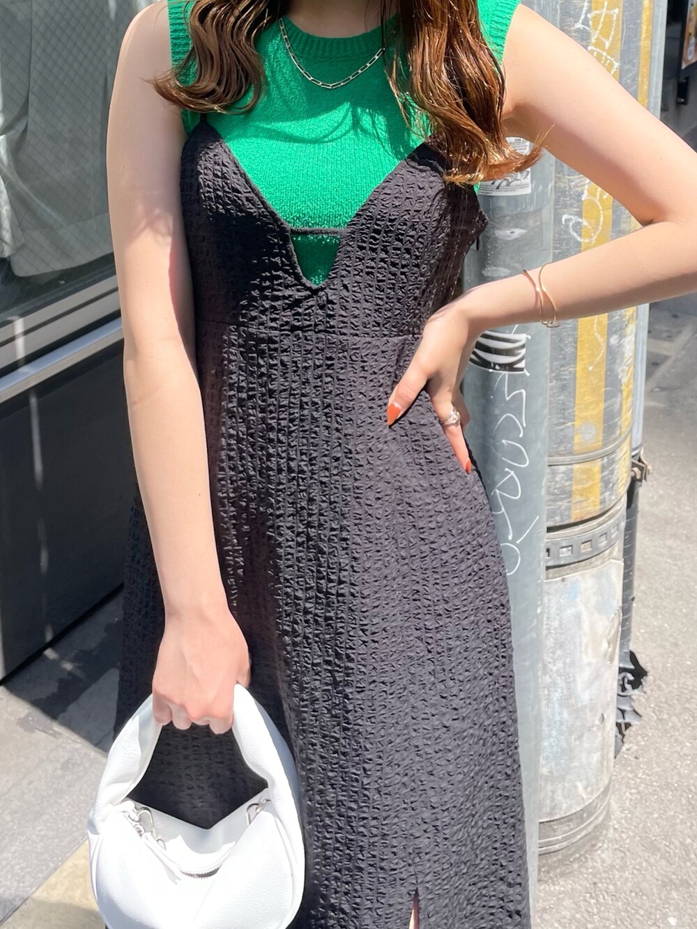 ホワイト系のハンドバッグ、ブラック系のサンダル、グリーン系のタンクトップを着用したレディースの春コーディネートの4枚目の写真