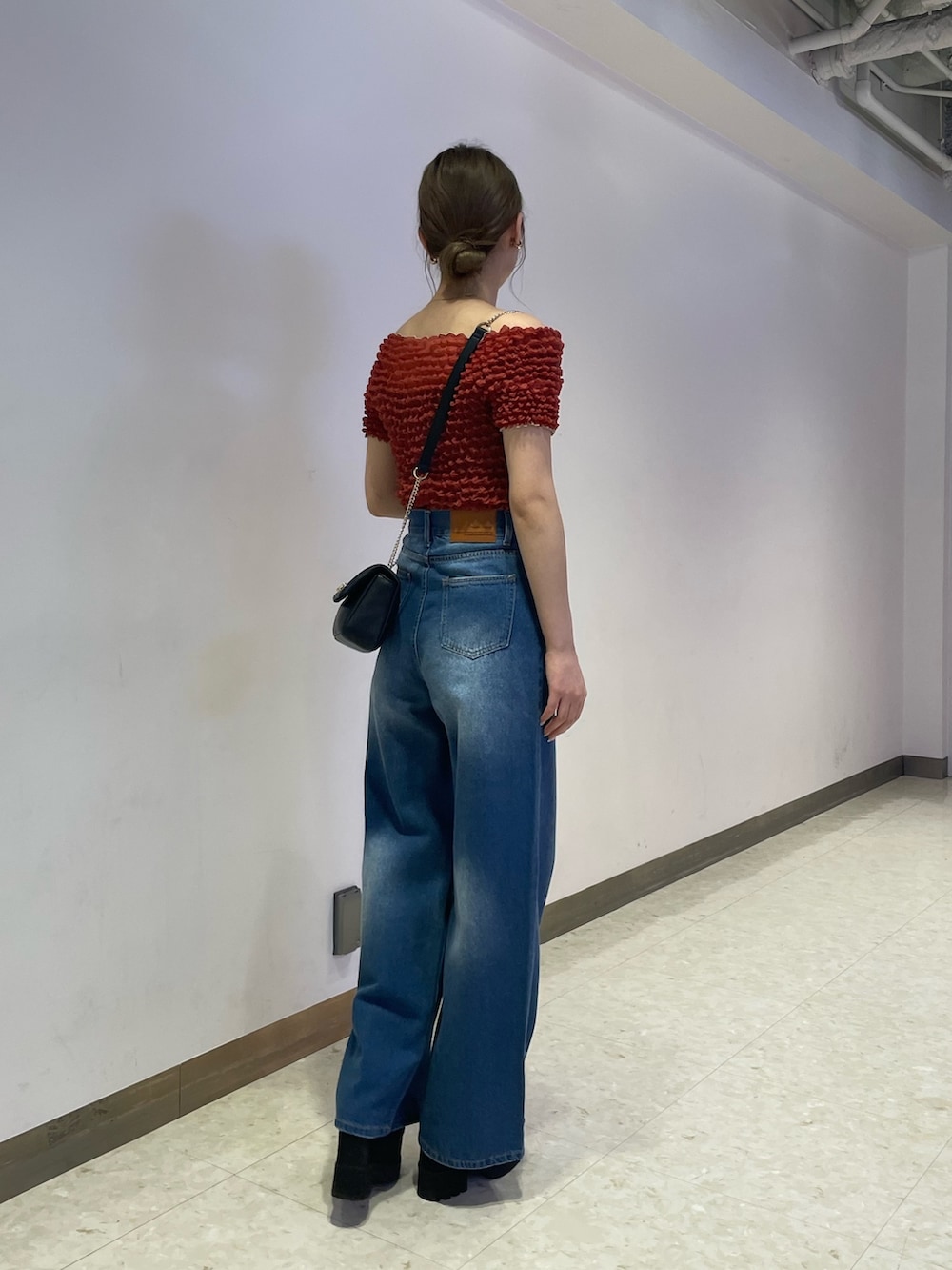 ブルー系のデニムパンツ、ブラック系のブーツ、レッド系のシャツ/ブラウスを着用したレディースの春コーディネートの3枚目の写真