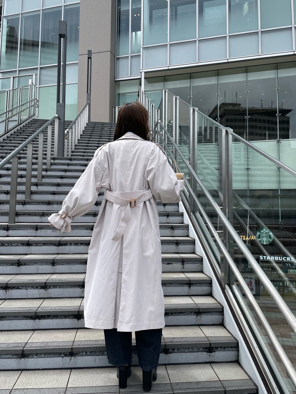 ホワイト系のトレンチコート、ブラック系のサンダル、ブラック系のデニムパンツを着用したレディースの春コーディネートの4枚目の写真