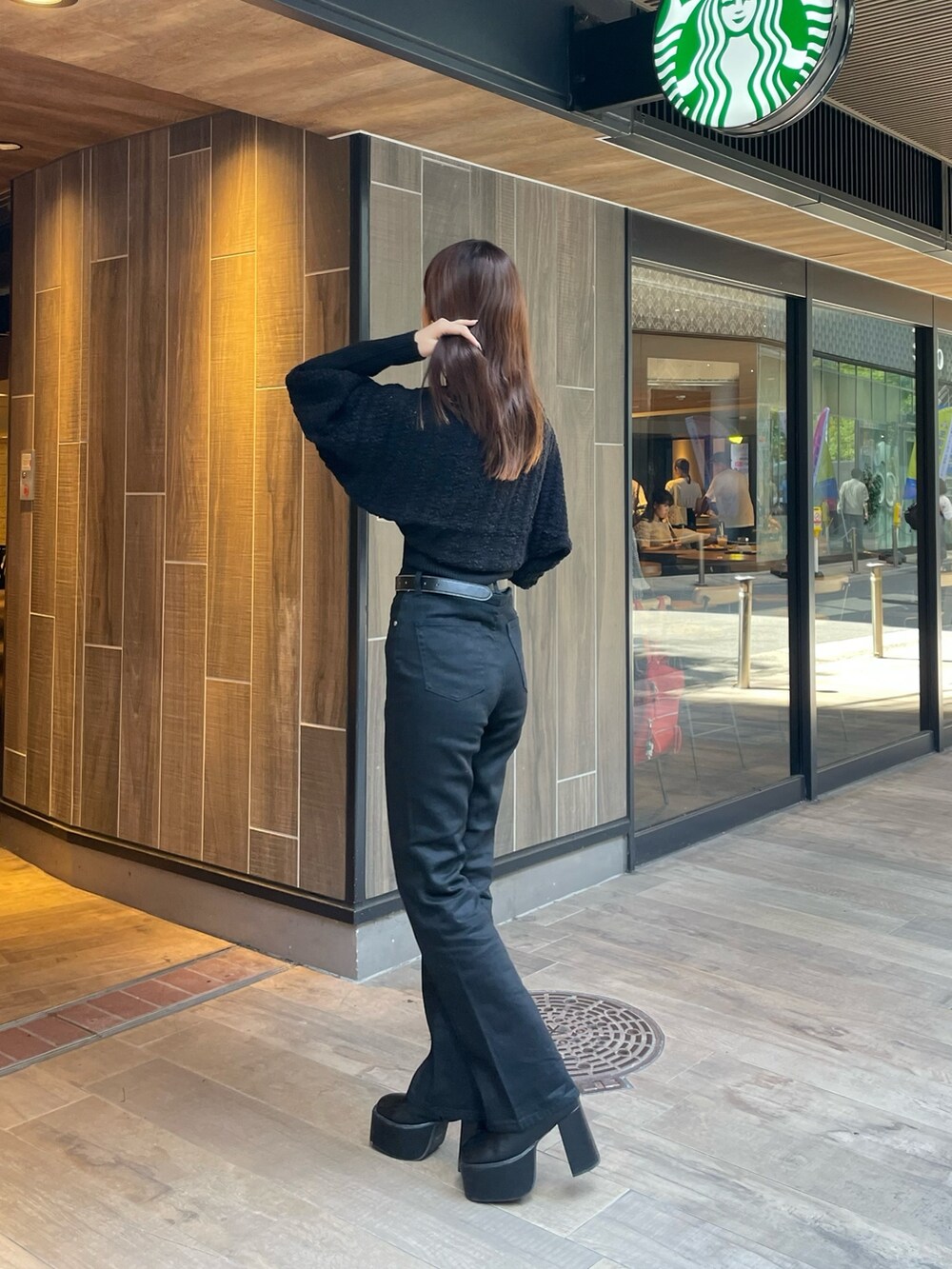 ブラック系のデニムパンツ、ブラック系のカーディガン/ボレロ、ブラック系のブーツを着用したレディースの秋コーディネートの3枚目の写真