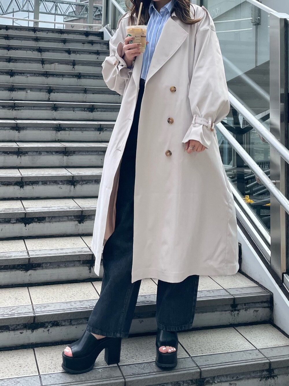 ホワイト系のトレンチコート、ブラック系のサンダル、ブラック系のデニムパンツを着用したレディースの春コーディネートの6枚目の写真