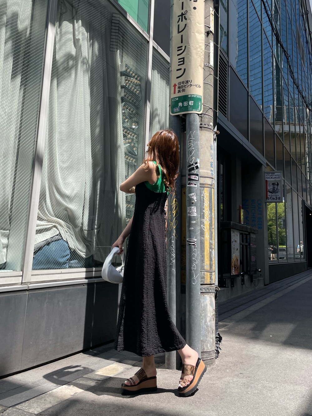 ホワイト系のハンドバッグ、ブラック系のサンダル、グリーン系のタンクトップを着用したレディースの春コーディネートの2枚目の写真