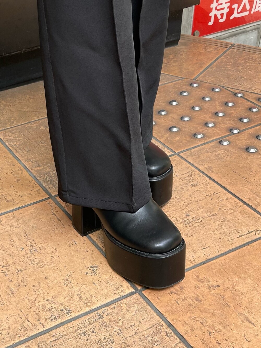 ブラック系のスラックス、ホワイト系のニット/セーター、ブラック系のブーツを着用したレディースの夏コーディネートの7枚目の写真