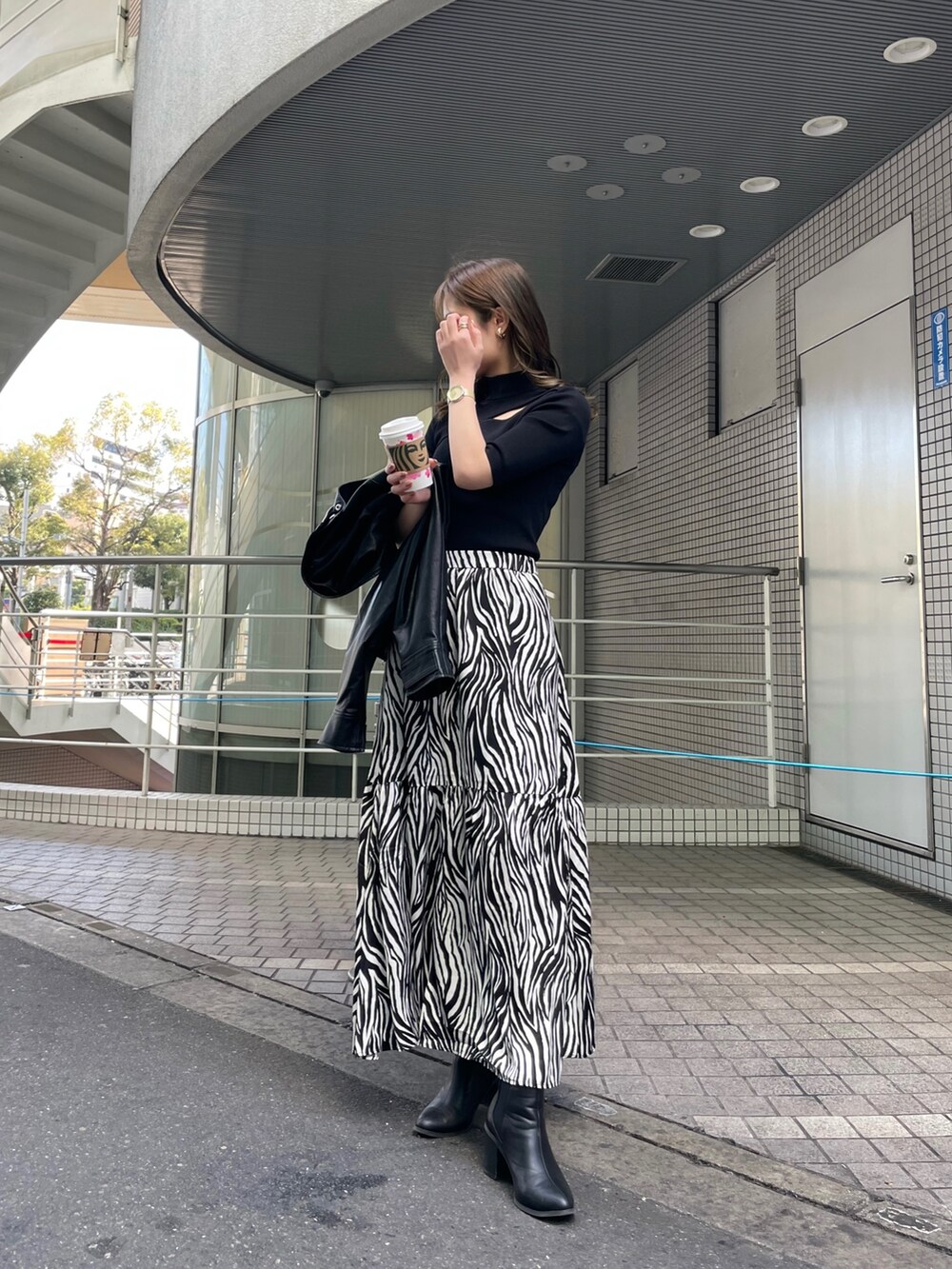 ブラック系のブルゾン、ホワイト系のスカート、ブラック系のニット/セーターを着用したレディースの春コーディネートの4枚目の写真