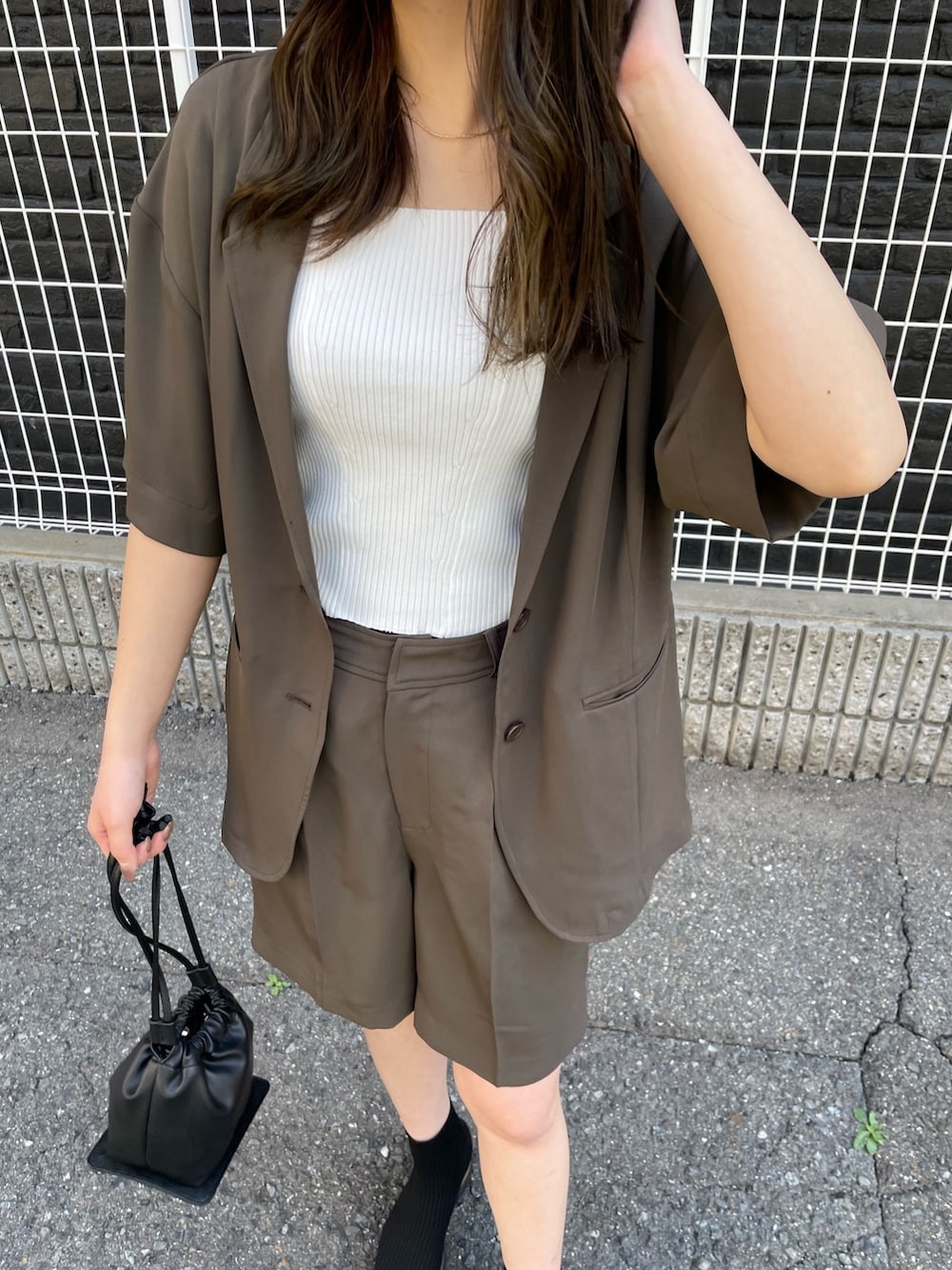 ブラウン系のテーラードジャケット、ホワイト系のタンクトップ、ブラウン系のスラックスを着用したレディースの春コーディネートの5枚目の写真