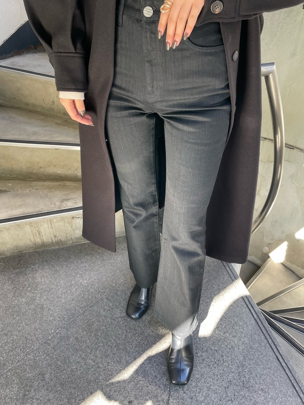 ブラック系のステンカラーコート、ホワイト系のニット/セーター、ブラック系のデニムパンツを着用したレディースの秋コーディネートの7枚目の写真