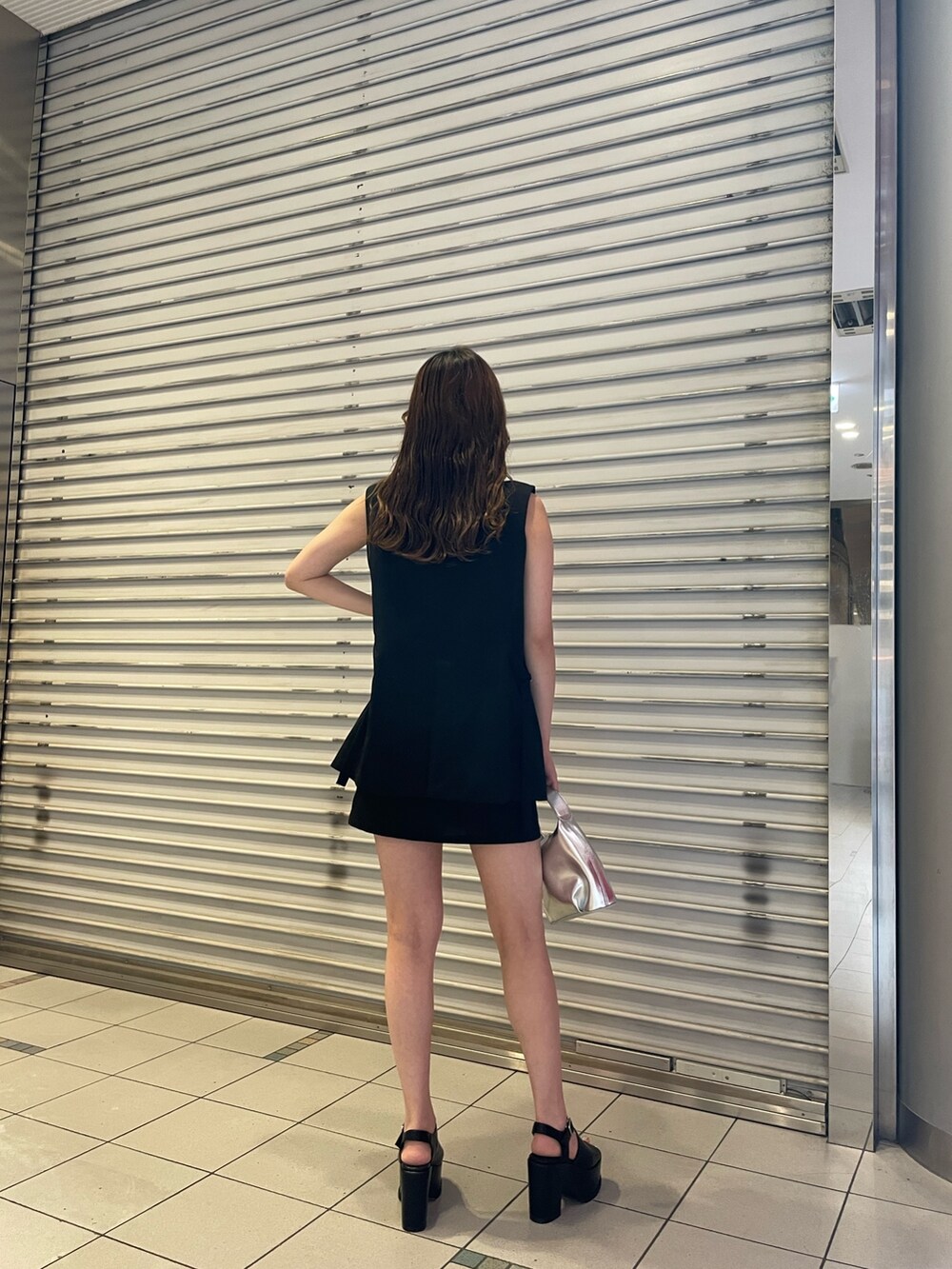 ブラック系のスカート、ホワイト系のタンクトップ、シルバー系のハンドバッグを着用したレディースの夏コーディネートの3枚目の写真