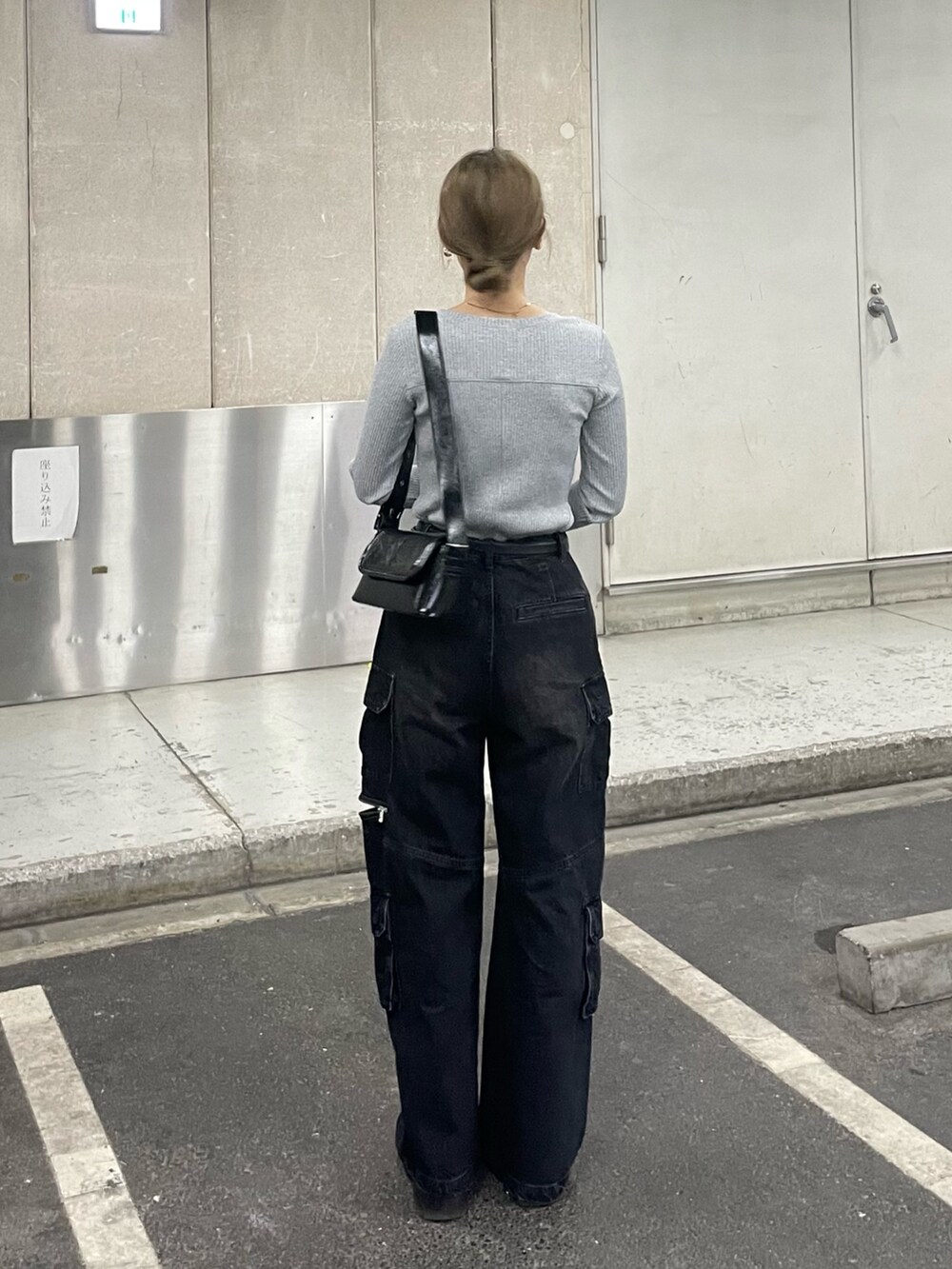 ブラック系のデニムパンツ、ブラック系のショルダーバッグ、グレー系のTシャツ/カットソーを着用したレディースの冬コーディネートの4枚目の写真