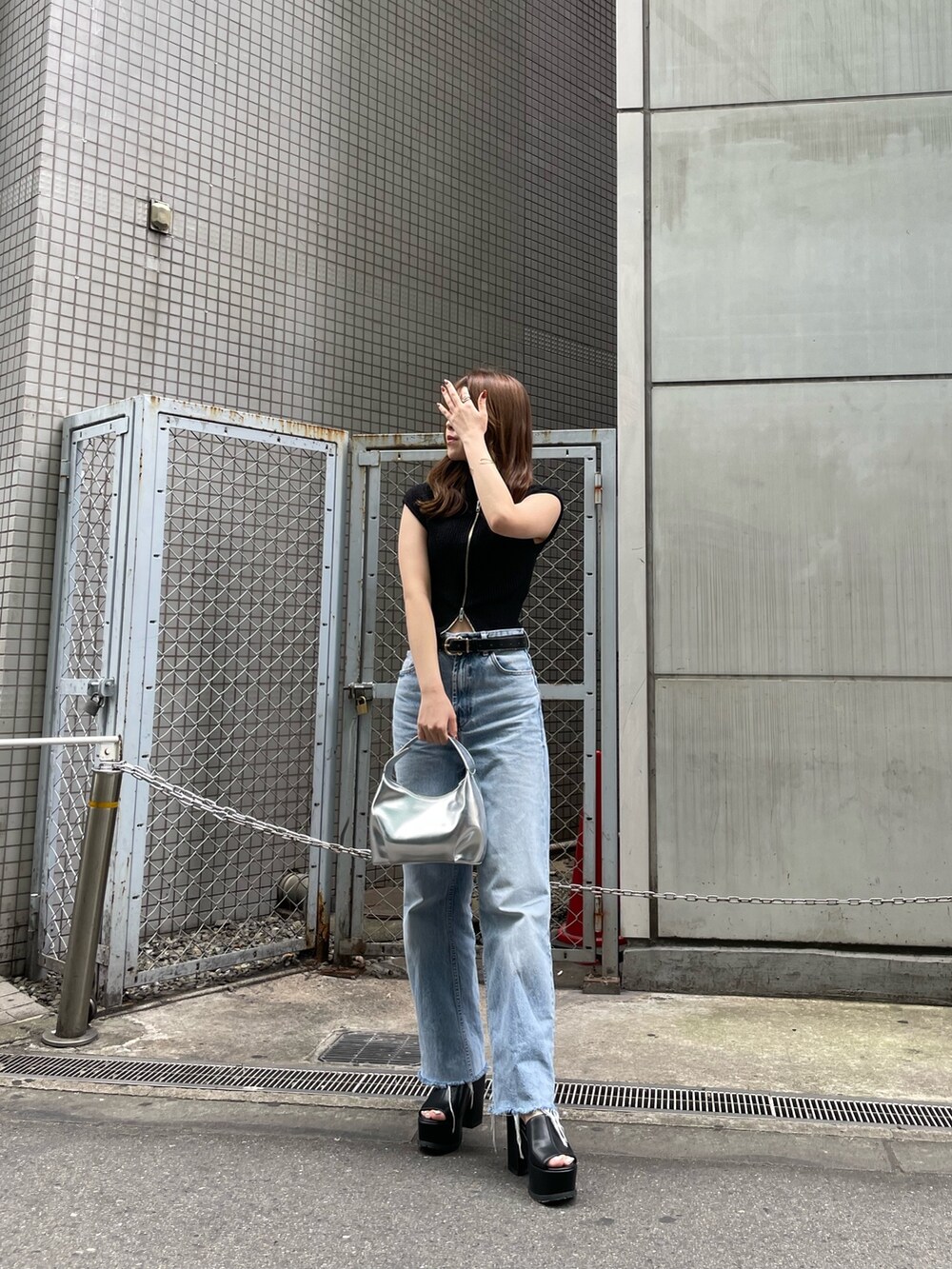 ブラック系のニット/セーター、シルバー系のハンドバッグ、ブラック系のサンダルを着用したレディースの春コーディネートの2枚目の写真