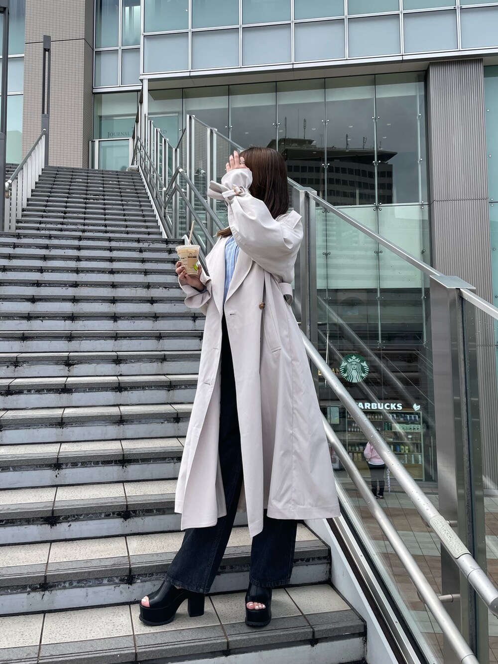 ホワイト系のトレンチコート、ブラック系のサンダル、ブラック系のデニムパンツを着用したレディースの春コーディネートの2枚目の写真