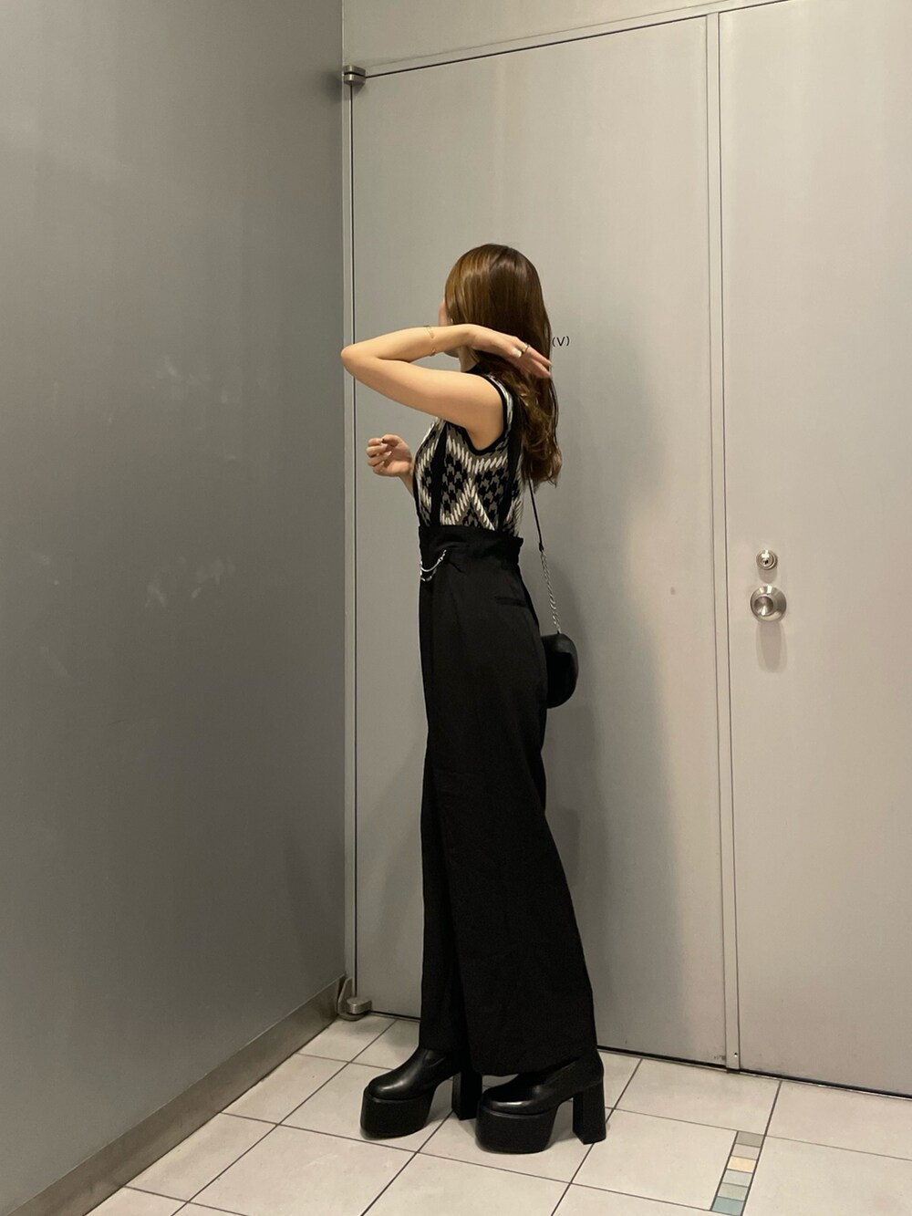 ブラウン系のニット/セーター、ブラック系のスラックス、ブラック系のハンドバッグを着用したレディースの夏コーディネートの3枚目の写真