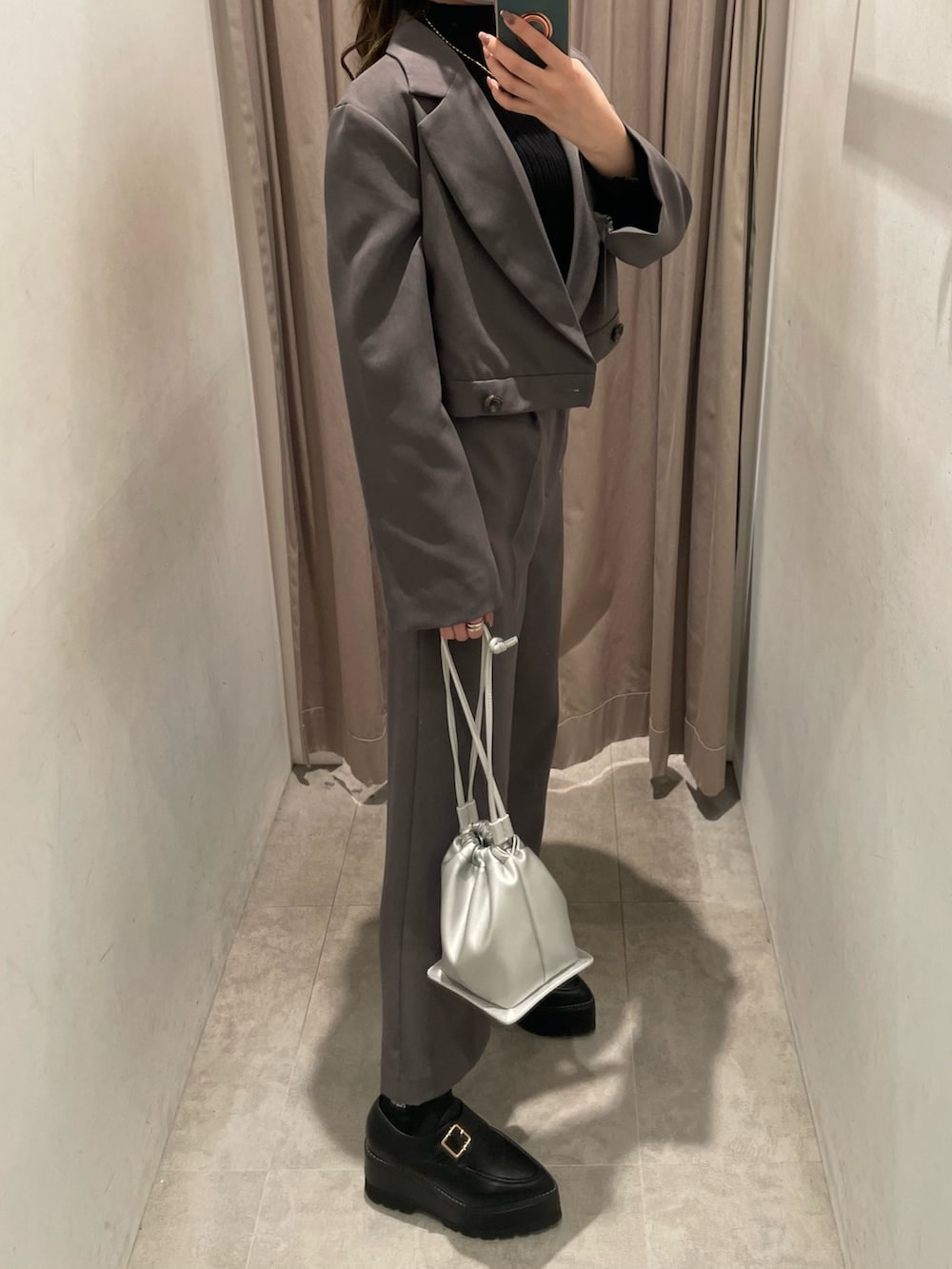 グレー系のテーラードジャケット、ブラック系のニット/セーター、シルバー系のハンドバッグを着用したレディースの春コーディネートの2枚目の写真