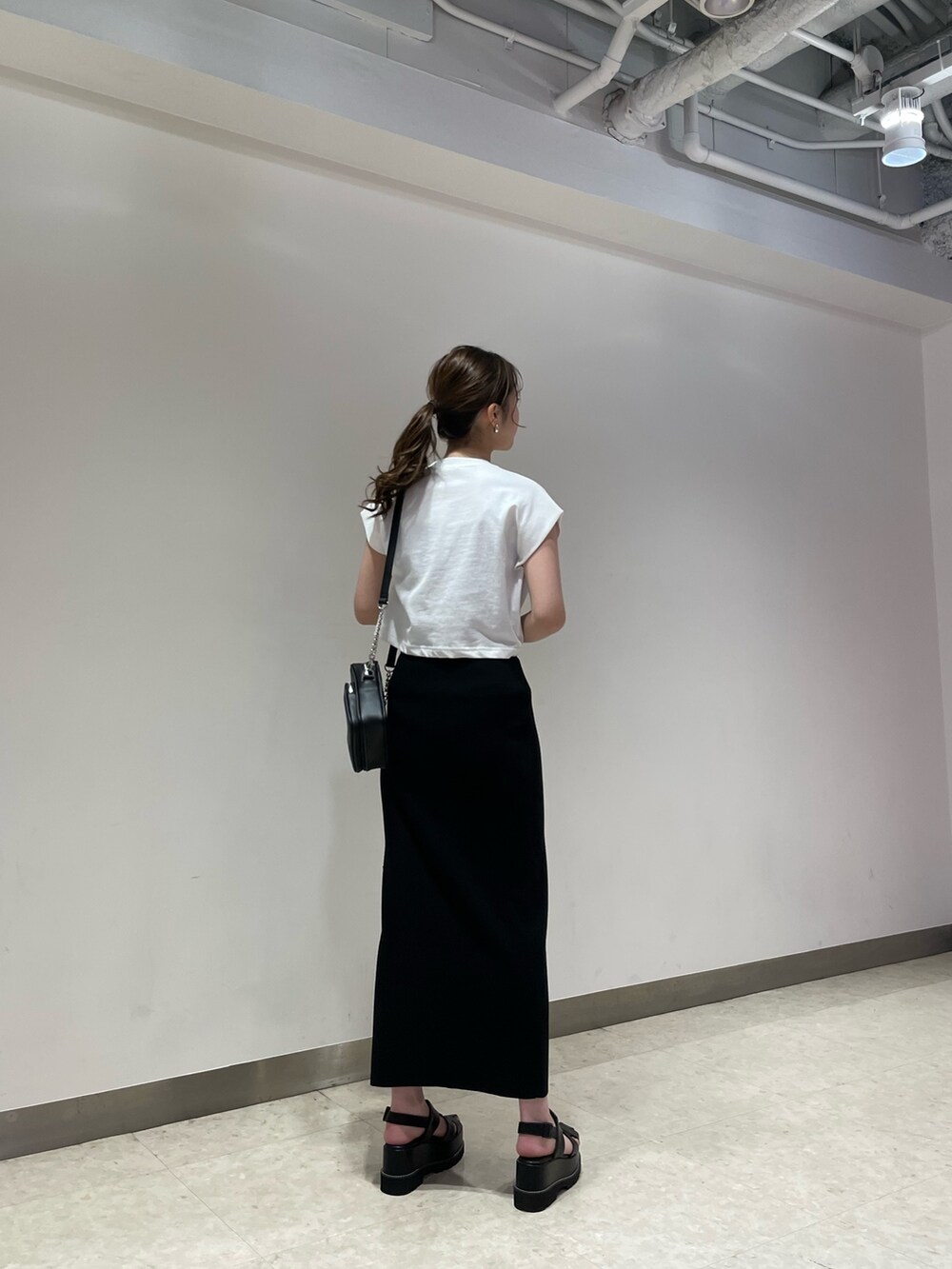 ホワイト系のTシャツ/カットソー、ブラック系のサンダル、ブラック系のショルダーバッグを着用したレディースの春コーディネートの3枚目の写真