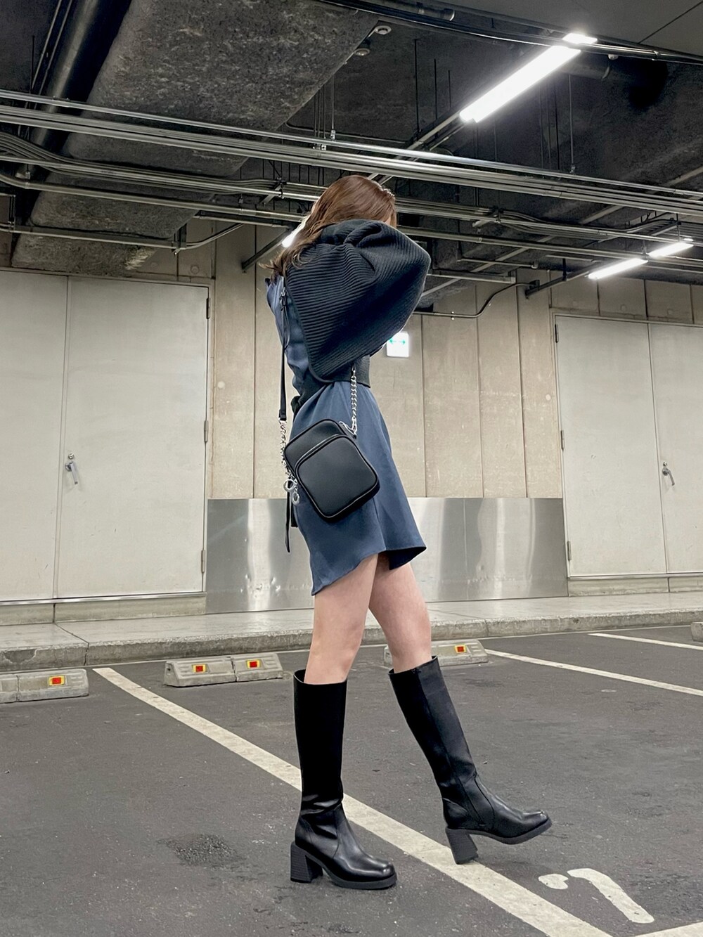 グレー系のワンピース、ブラック系のショルダーバッグ、ブラック系のブーツを着用したレディースの冬コーディネートの2枚目の写真
