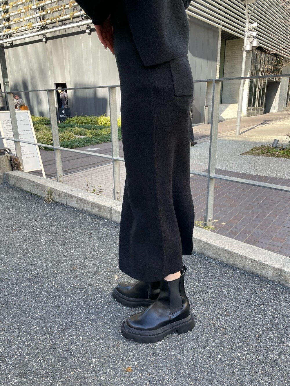 ブラック系のニット/セーター、ブラック系のスカート、ブラック系のブーツを着用したレディースの冬コーディネートの7枚目の写真