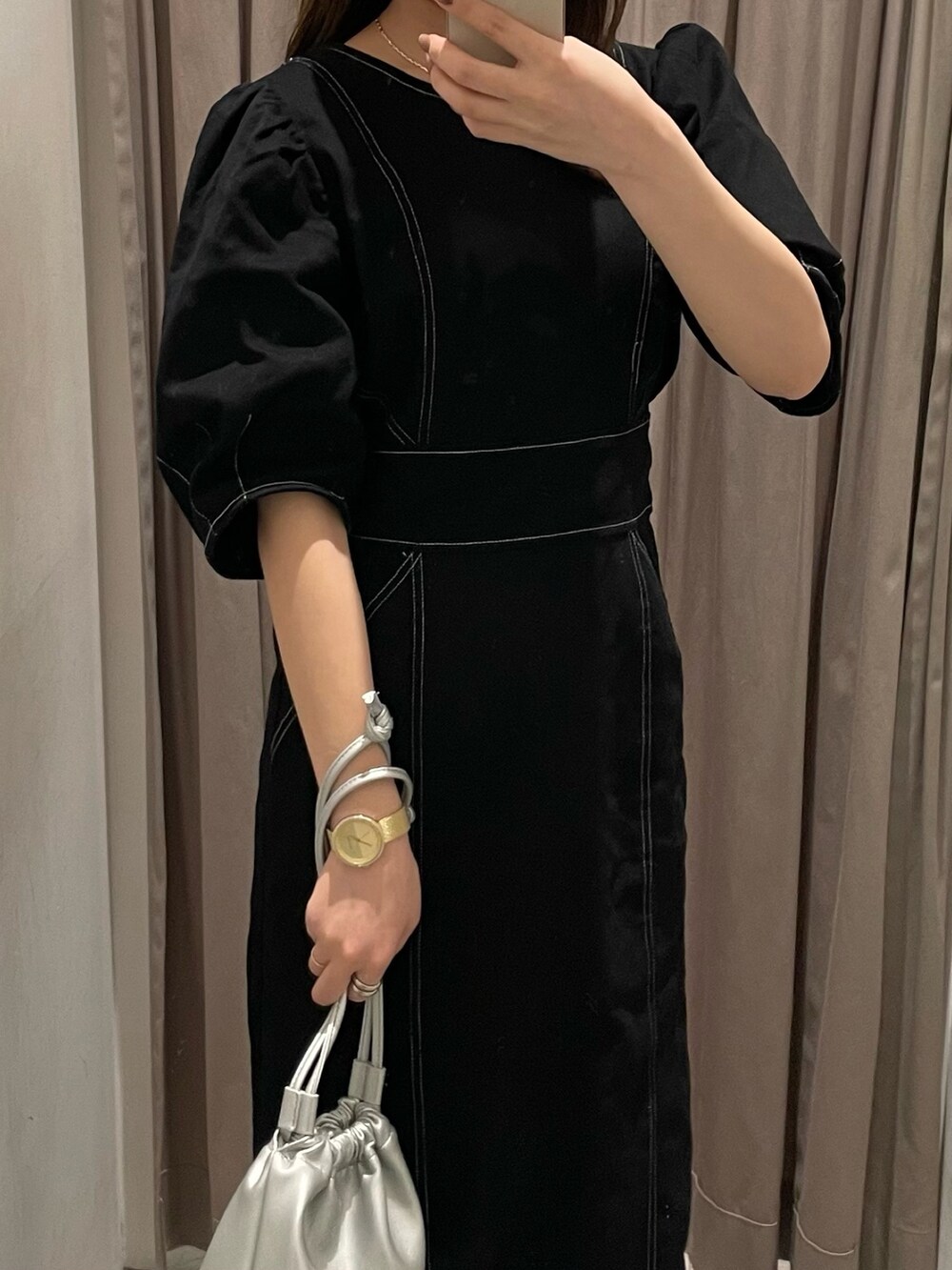 ブラック系のブーツ、ブラック系のワンピース、シルバー系のハンドバッグを着用したレディースの春コーディネートの5枚目の写真