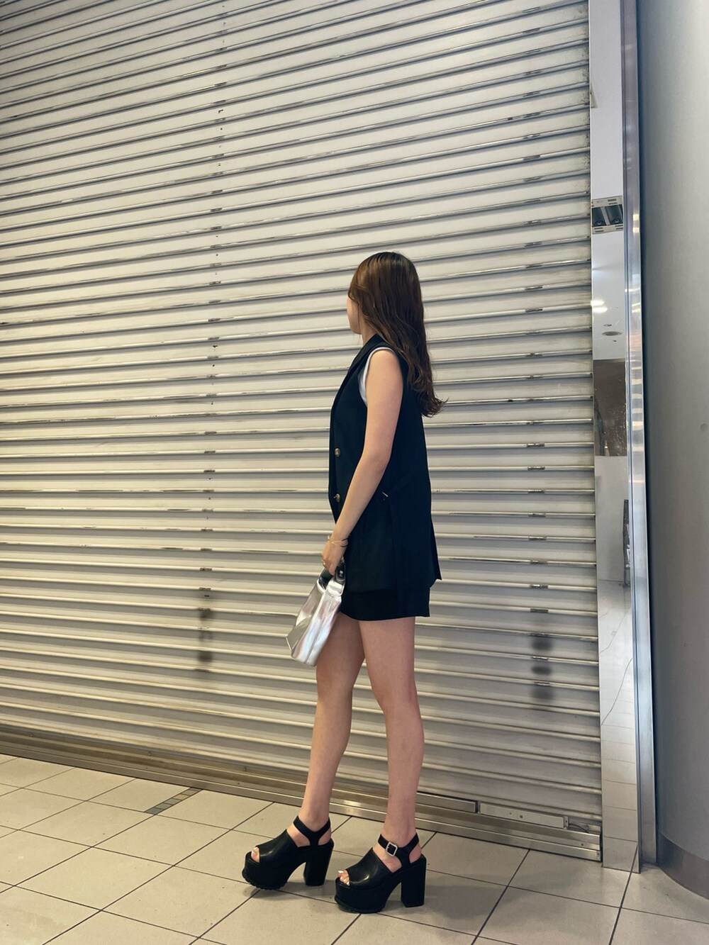 ブラック系のスカート、ホワイト系のタンクトップ、シルバー系のハンドバッグを着用したレディースの夏コーディネートの2枚目の写真