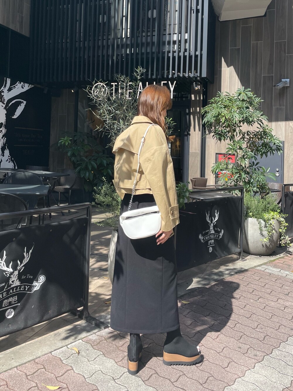 ホワイト系のハンドバッグ、ブラック系のブーツ、ブラック系のスカートを着用したレディースの春コーディネートの3枚目の写真