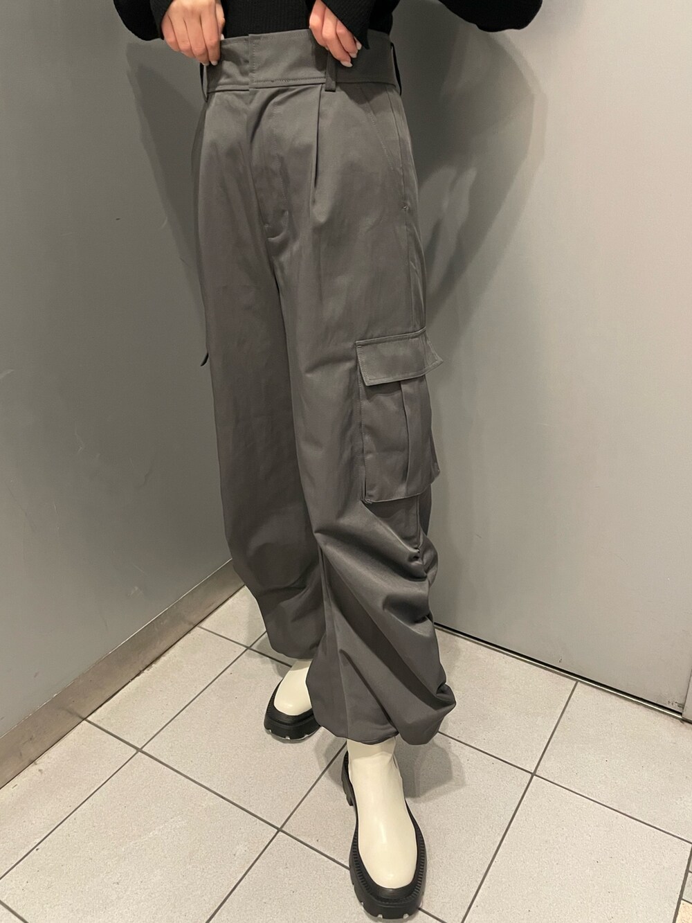 ブラック系のニット/セーター、グレー系のカーゴパンツ、ホワイト系のブーツを着用したレディースの冬コーディネートの7枚目の写真