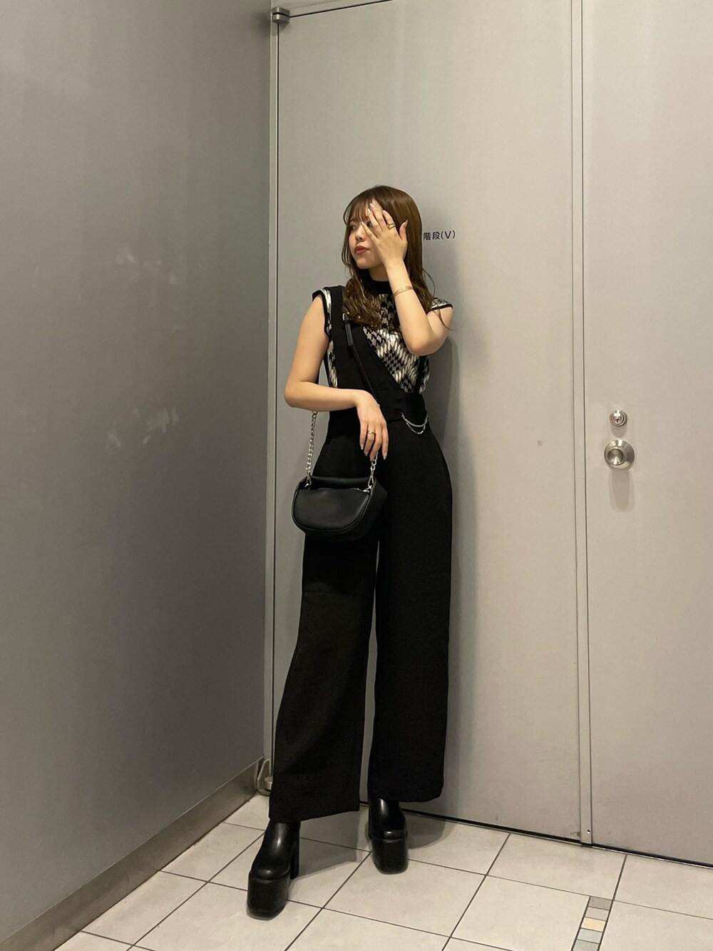 ブラウン系のニット/セーター、ブラック系のスラックス、ブラック系のハンドバッグを着用したレディースの夏コーディネートの2枚目の写真