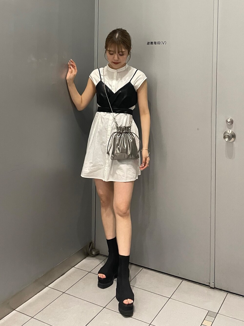 グレー系のショルダーバッグ、ブラック系のブーツ、ブラック系のワンピースを着用したレディースの春コーディネートの2枚目の写真