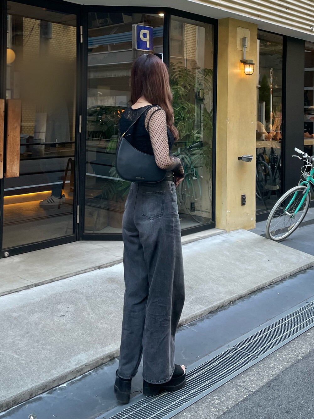 ブラック系のデニムパンツ、ブラック系のTシャツ/カットソー、ブラック系のブーツを着用したレディースの秋コーディネートの2枚目の写真