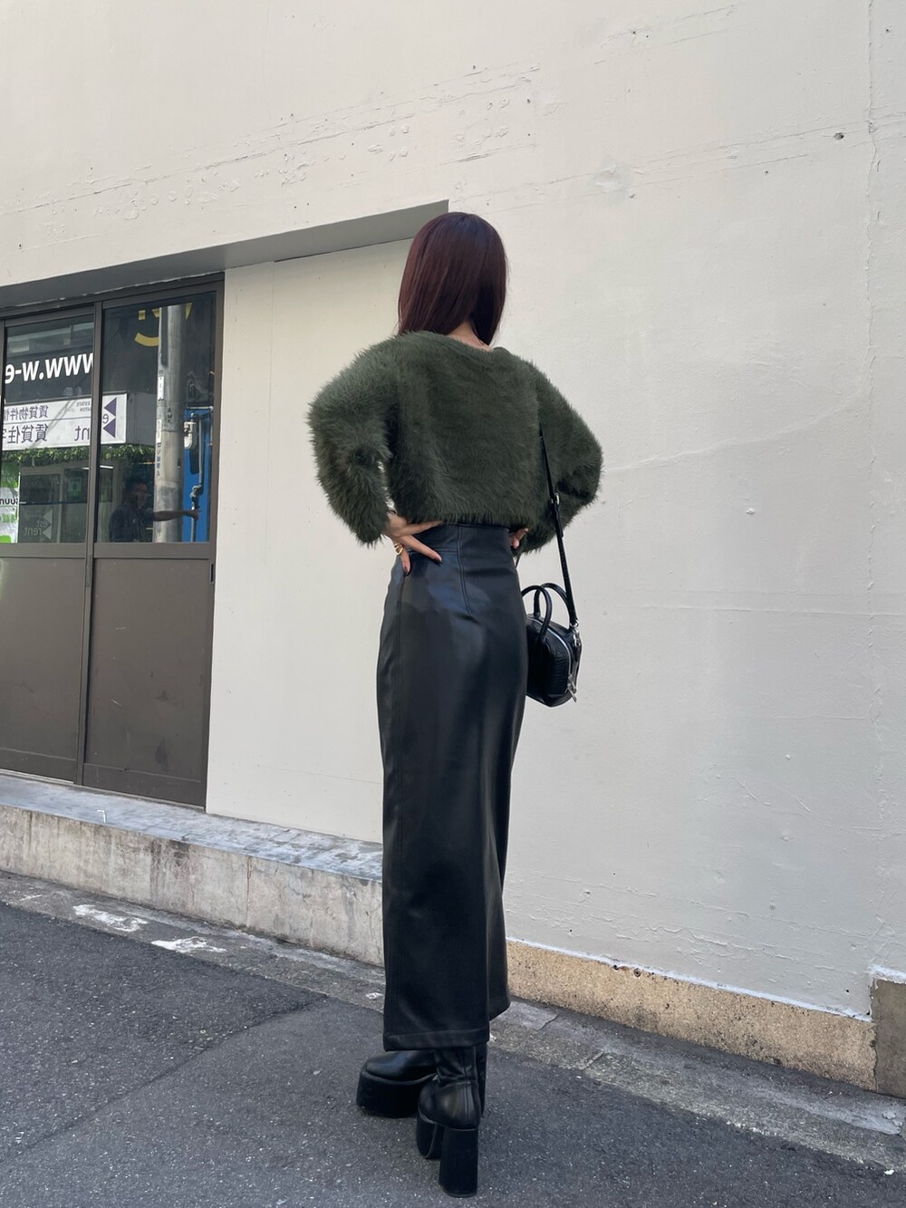 グリーン系のニット/セーター、ブラック系のボストンバッグ、ブラック系のスカートを着用したレディースの秋コーディネートの3枚目の写真