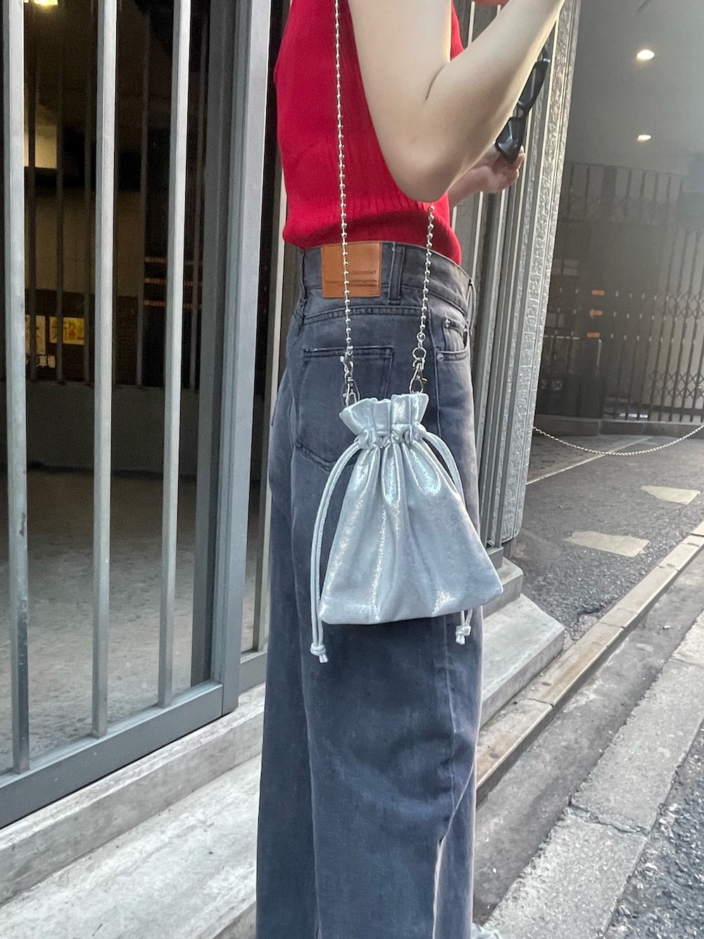 レッド系のニット/セーター、ブラック系のサンダル、ブラック系のデニムパンツを着用したレディースの春コーディネートの6枚目の写真