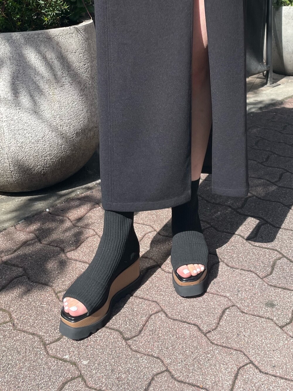 ホワイト系のハンドバッグ、ブラック系のブーツ、ブラック系のスカートを着用したレディースの春コーディネートの9枚目の写真