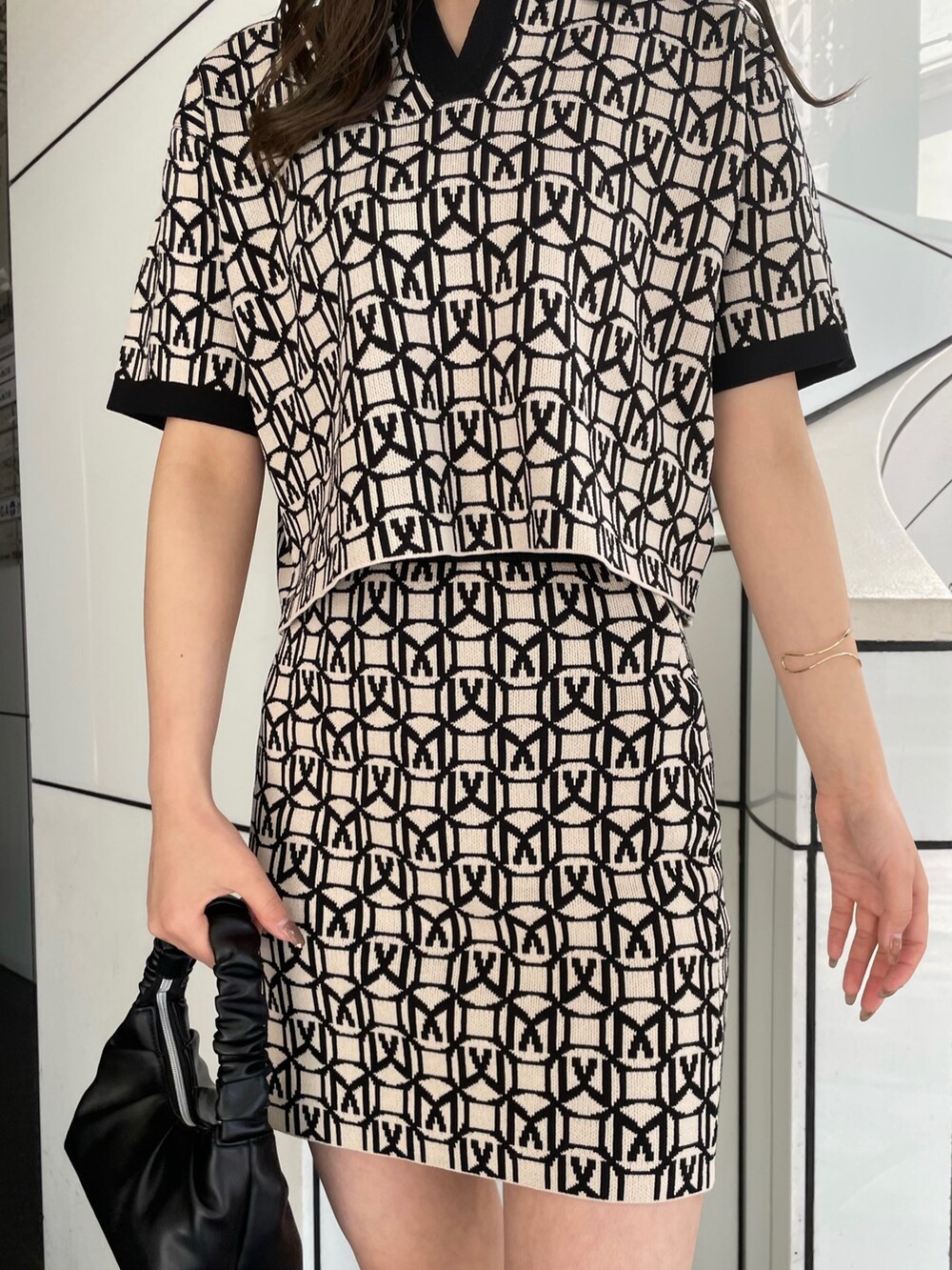 ブラック系のポロシャツ、ブラック系のスカート、ブラック系のブーツを着用したレディースの春コーディネートの6枚目の写真