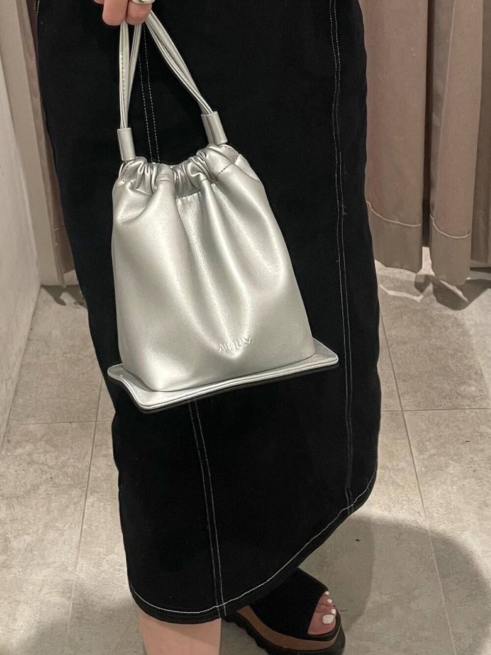 ブラック系のブーツ、ブラック系のワンピース、シルバー系のハンドバッグを着用したレディースの春コーディネートの6枚目の写真