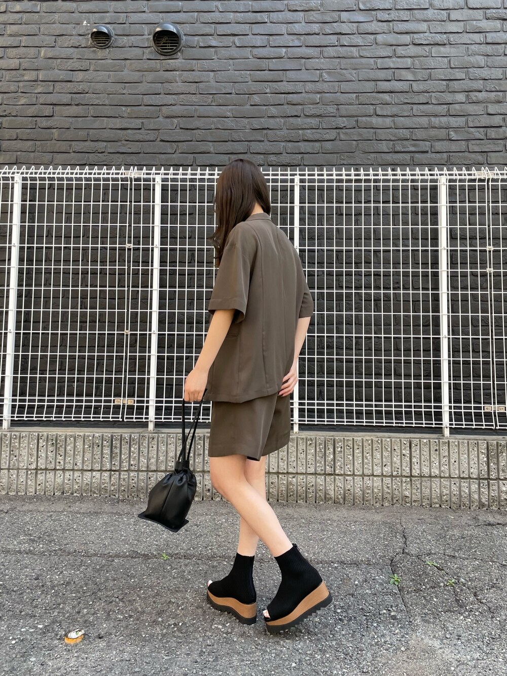 ブラウン系のテーラードジャケット、ホワイト系のタンクトップ、ブラウン系のスラックスを着用したレディースの春コーディネートの3枚目の写真