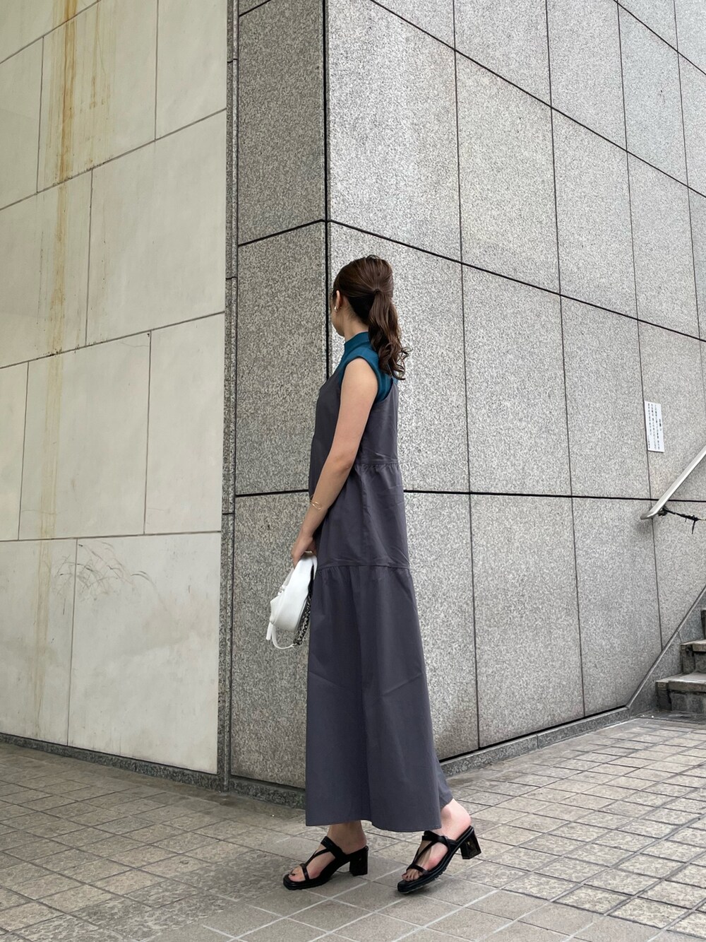 グレー系のワンピース、ブルー系のニット/セーター、ホワイト系のハンドバッグを着用したレディースの春コーディネートの2枚目の写真