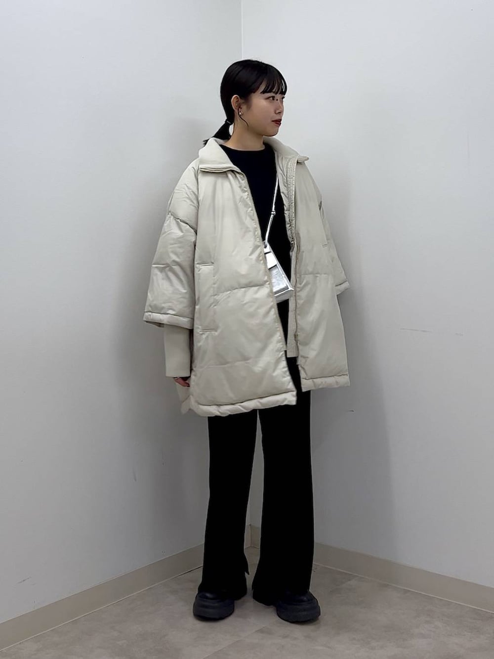 シルバー系のショルダーバッグ、ホワイト系のポンチョ、ブラック系のTシャツ/カットソーを着用したレディースの秋コーディネートの6枚目の写真