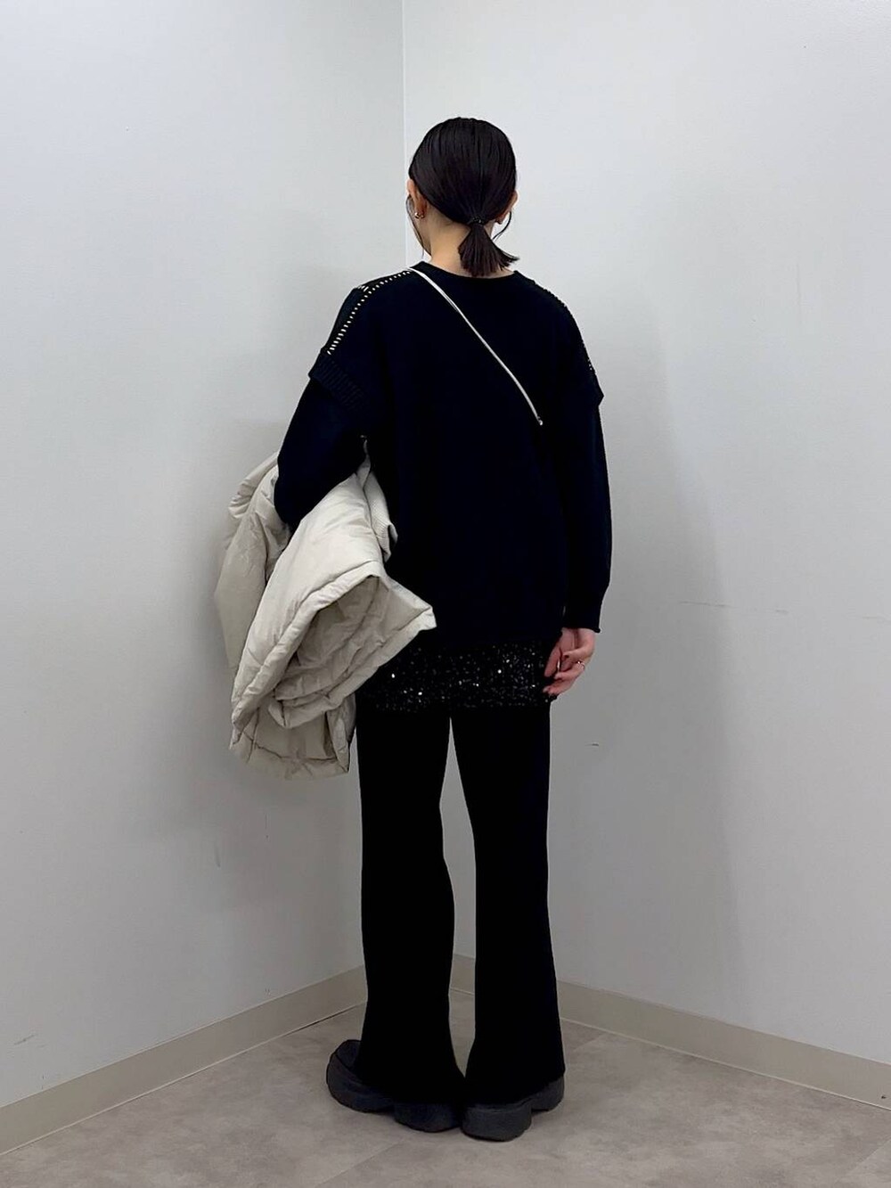 シルバー系のショルダーバッグ、ホワイト系のポンチョ、ブラック系のTシャツ/カットソーを着用したレディースの秋コーディネートの9枚目の写真