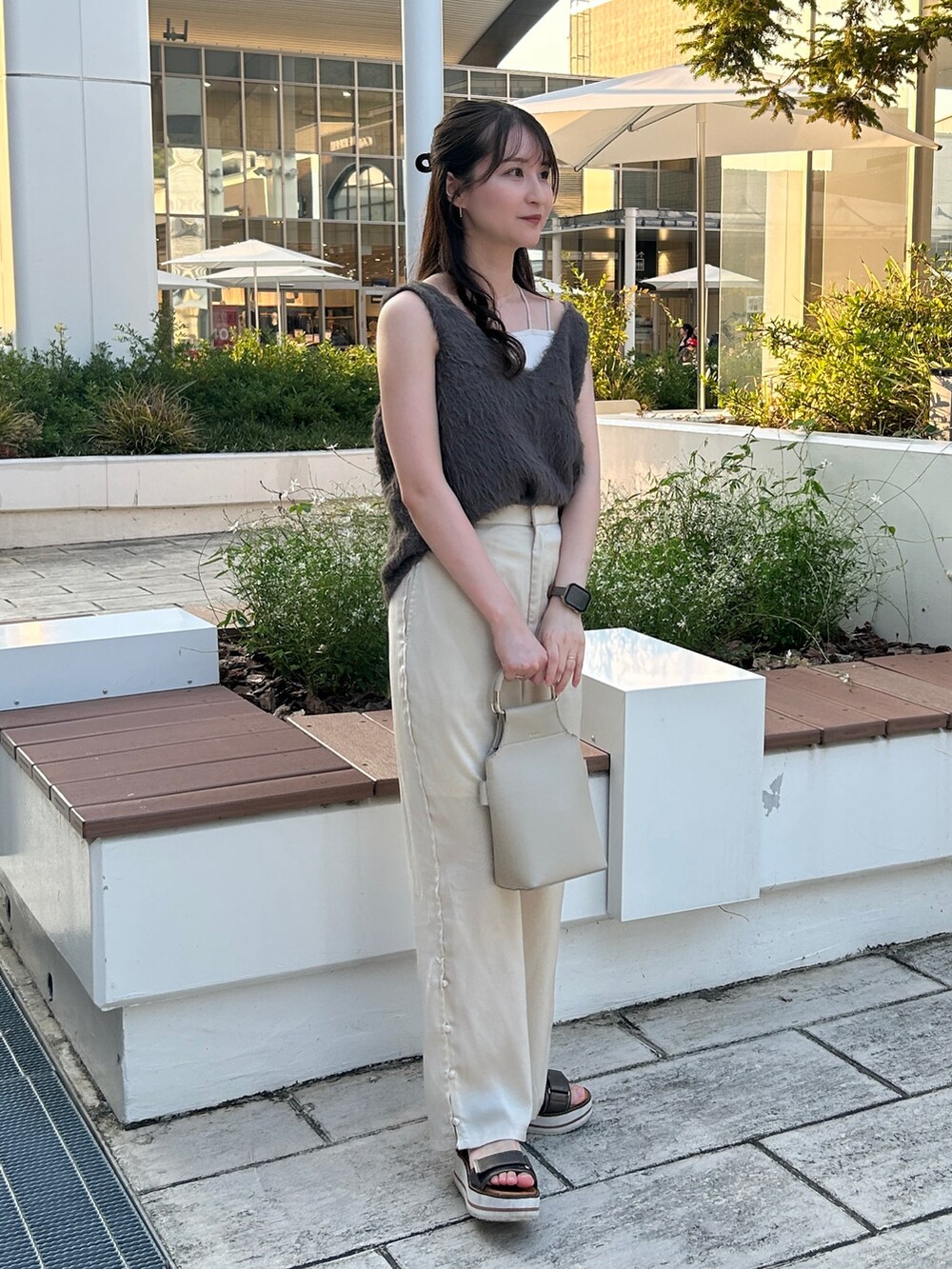 グレー系のベスト、ホワイト系のハンドバッグ、ホワイト系のその他パンツを着用したレディースの秋コーディネートの2枚目の写真