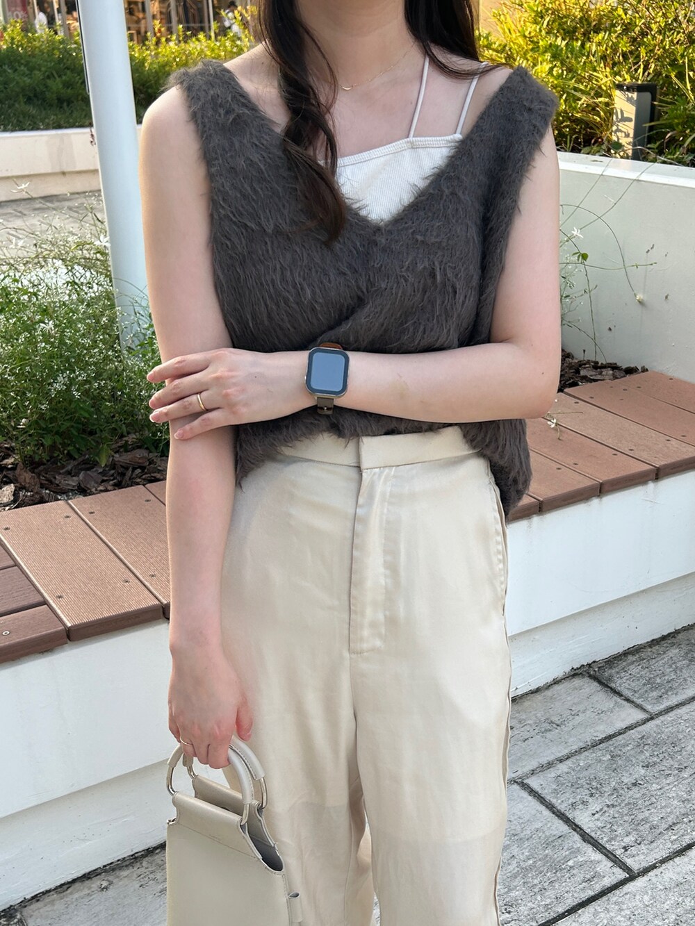 グレー系のベスト、ホワイト系のハンドバッグ、ホワイト系のその他パンツを着用したレディースの秋コーディネートの3枚目の写真