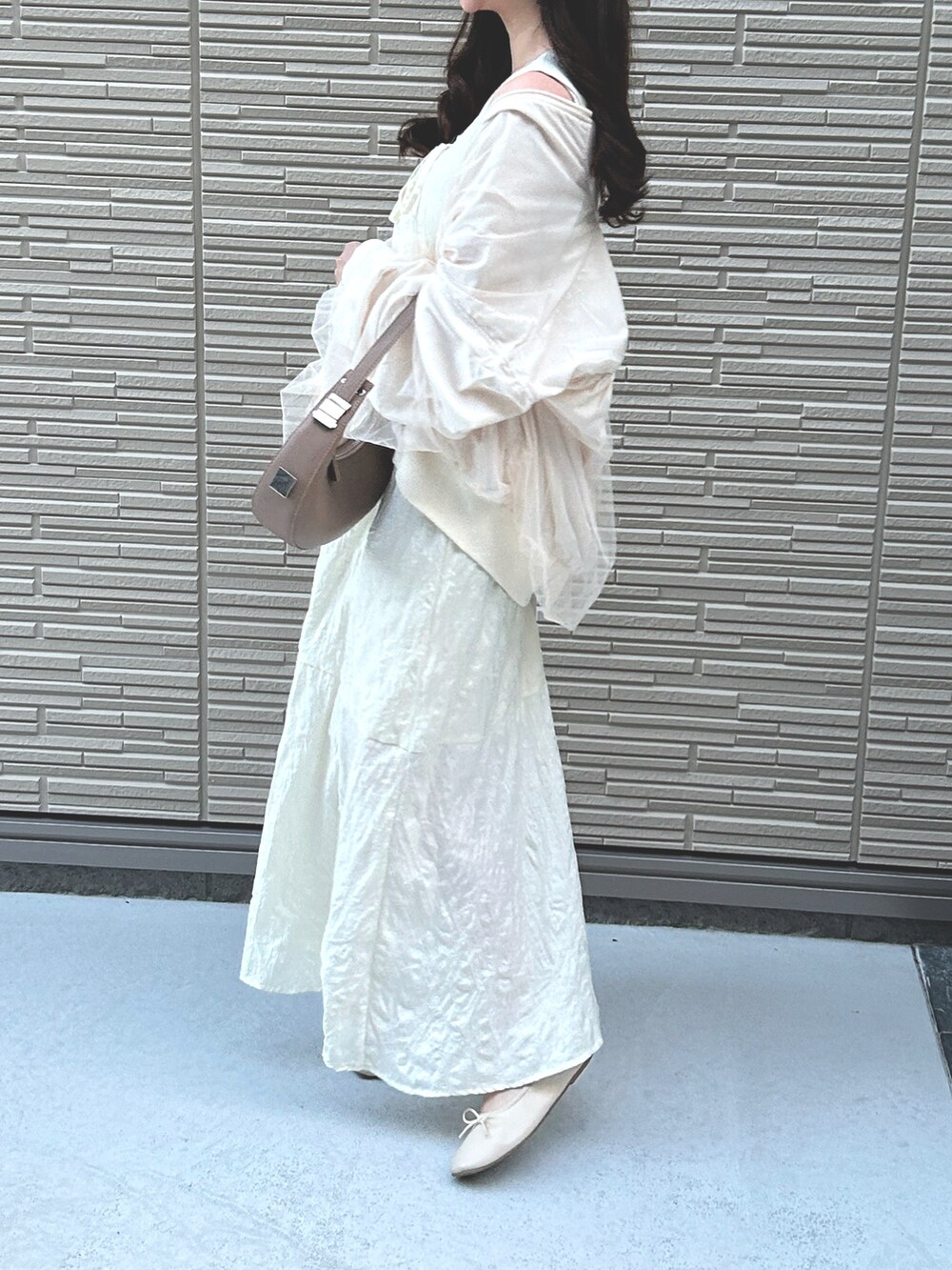 ホワイト系のブルゾン、ベージュ系のハンドバッグ、ホワイト系のパンプスを着用したレディースの秋コーディネートの2枚目の写真