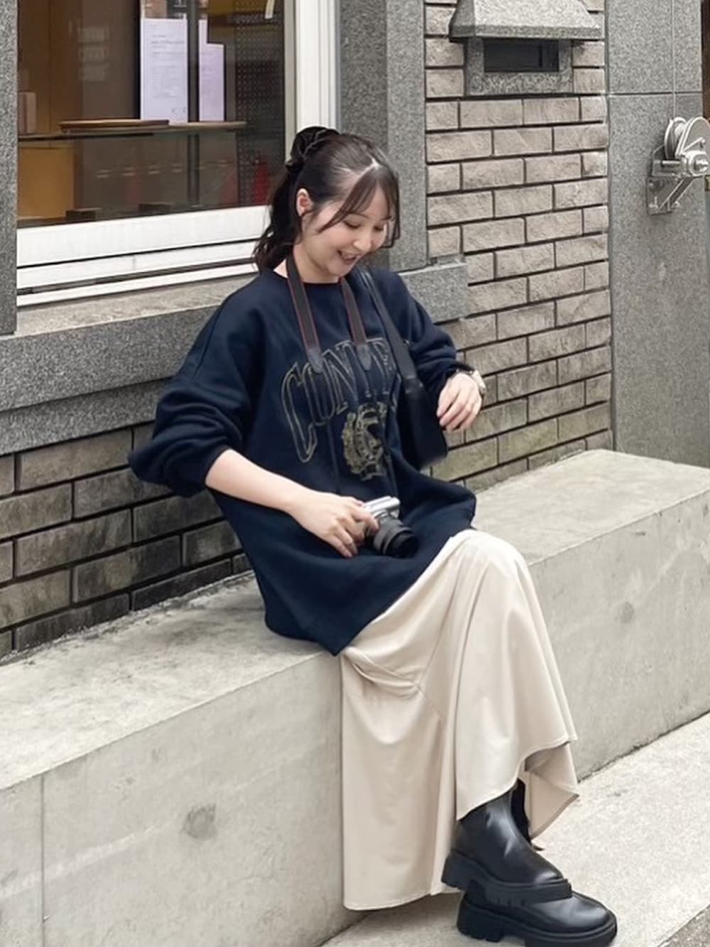 ブルー系のスウェット、ブラック系のブーツ、ホワイト系のスカートを着用したレディースの秋コーディネートの2枚目の写真