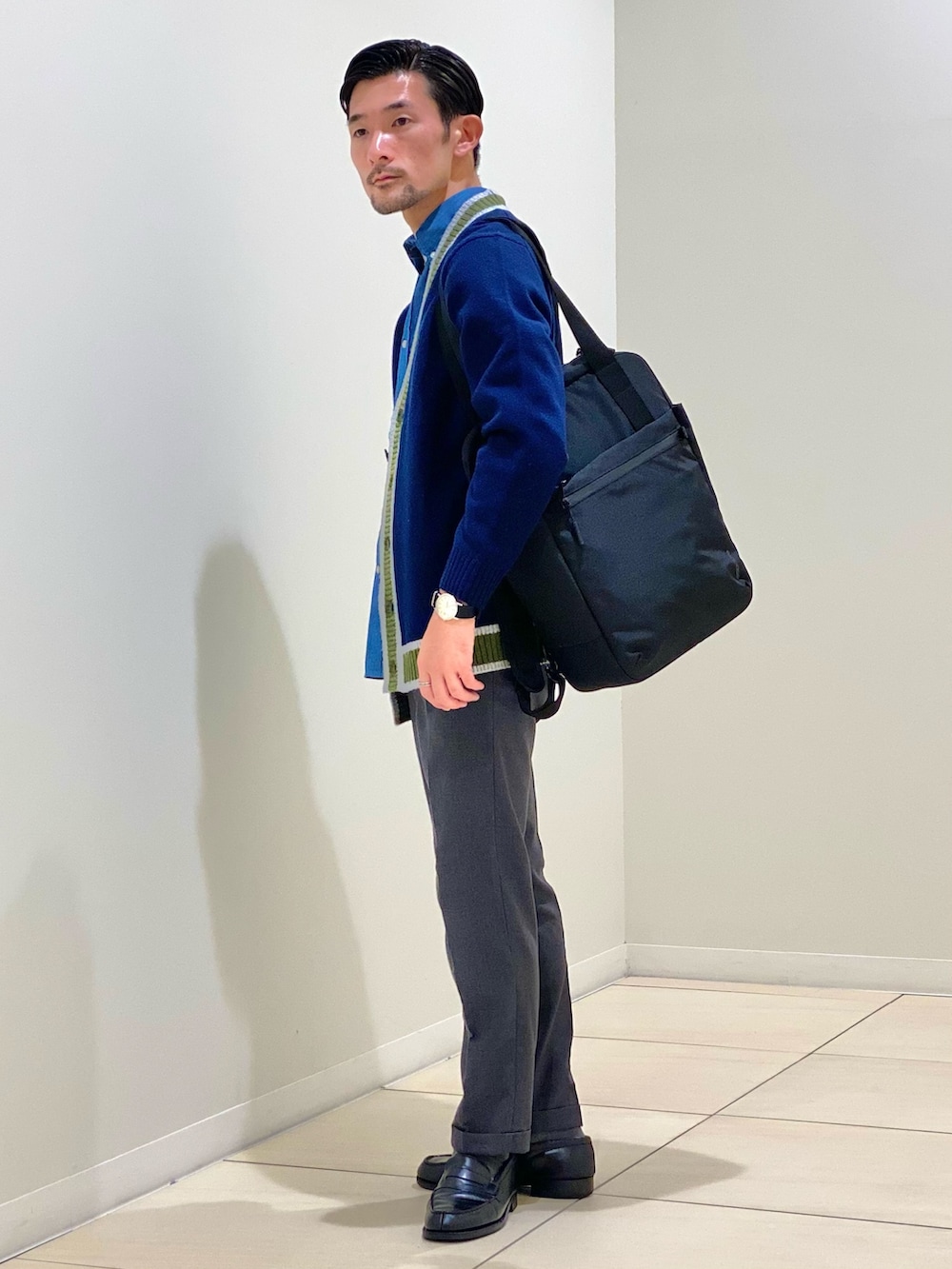ブラック系のトートバッグ、ブルー系のカーディガン/ボレロ、ブルー系のシャツ/ブラウスを着用したメンズの秋コーディネートの6枚目の写真