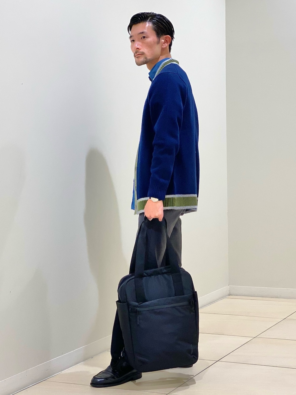 ブラック系のトートバッグ、ブルー系のカーディガン/ボレロ、ブルー系のシャツ/ブラウスを着用したメンズの秋コーディネートの3枚目の写真