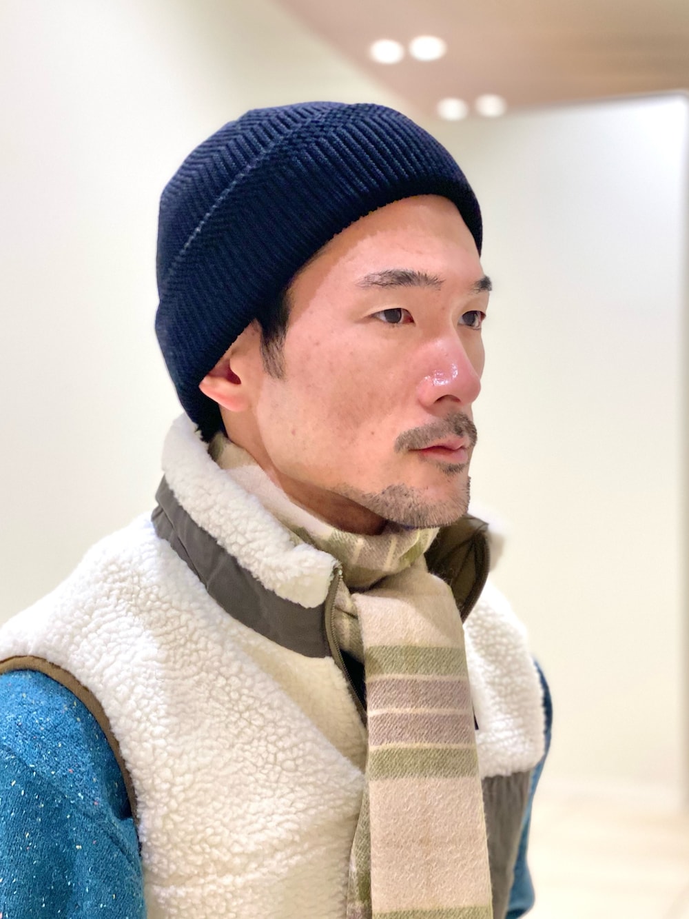 ホワイト系のダウンベスト、グリーン系のニット/セーター、グリーン系のマフラーを着用したメンズの冬コーディネートの7枚目の写真