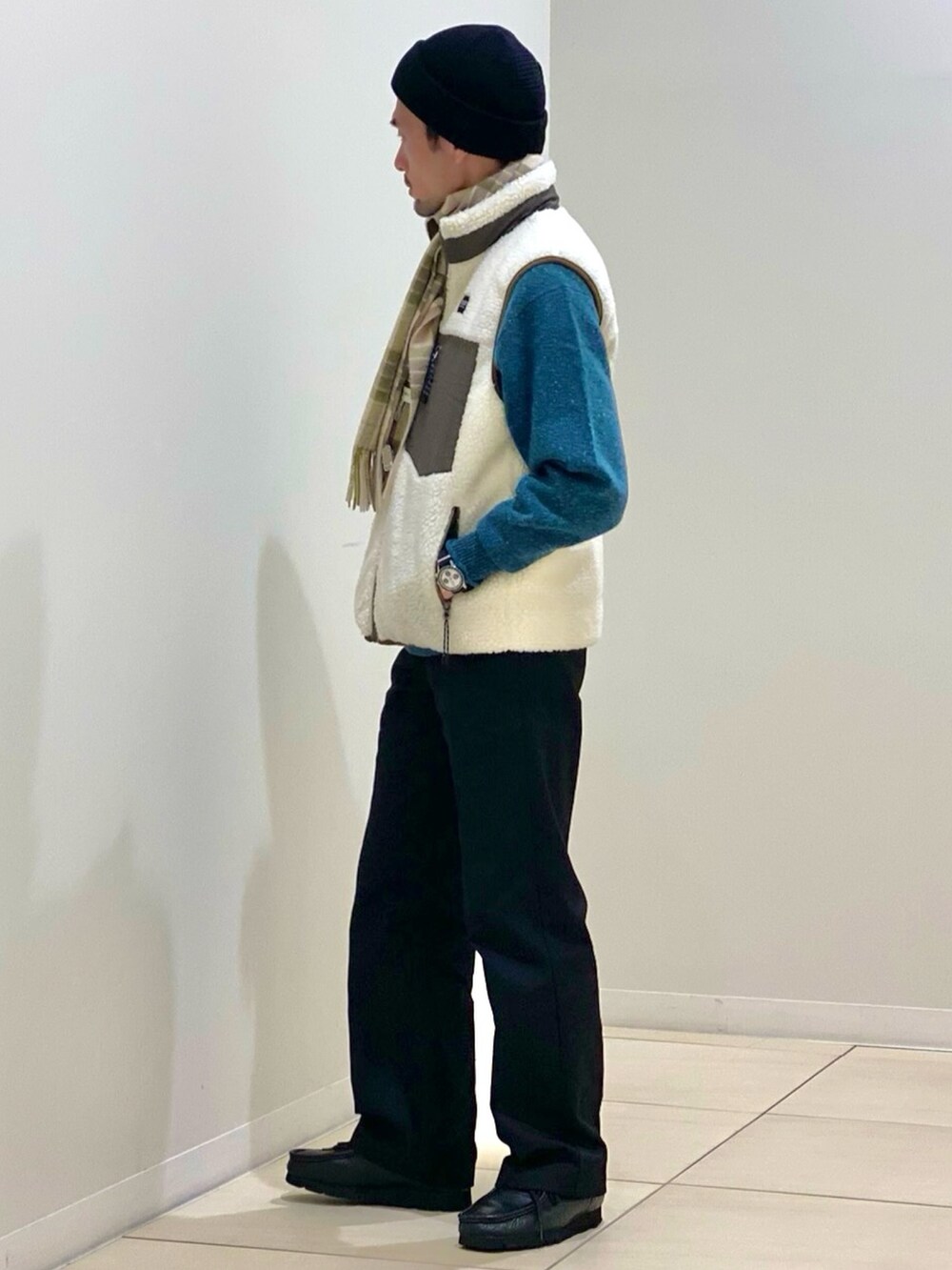 ホワイト系のダウンベスト、グリーン系のニット/セーター、グリーン系のマフラーを着用したメンズの冬コーディネートの3枚目の写真