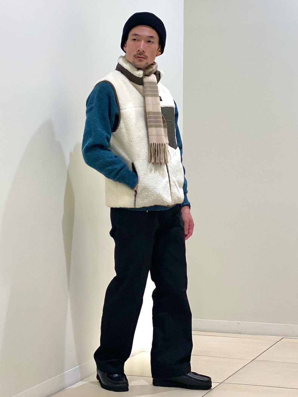 ホワイト系のダウンベスト、グリーン系のニット/セーター、グリーン系のマフラーを着用したメンズの冬コーディネートの5枚目の写真