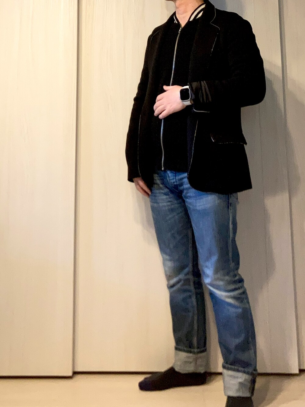 ブラック系のニット/セーター、ブラック系のテーラードジャケット、ブルー系のデニムパンツを着用したメンズの冬コーディネートの2枚目の写真