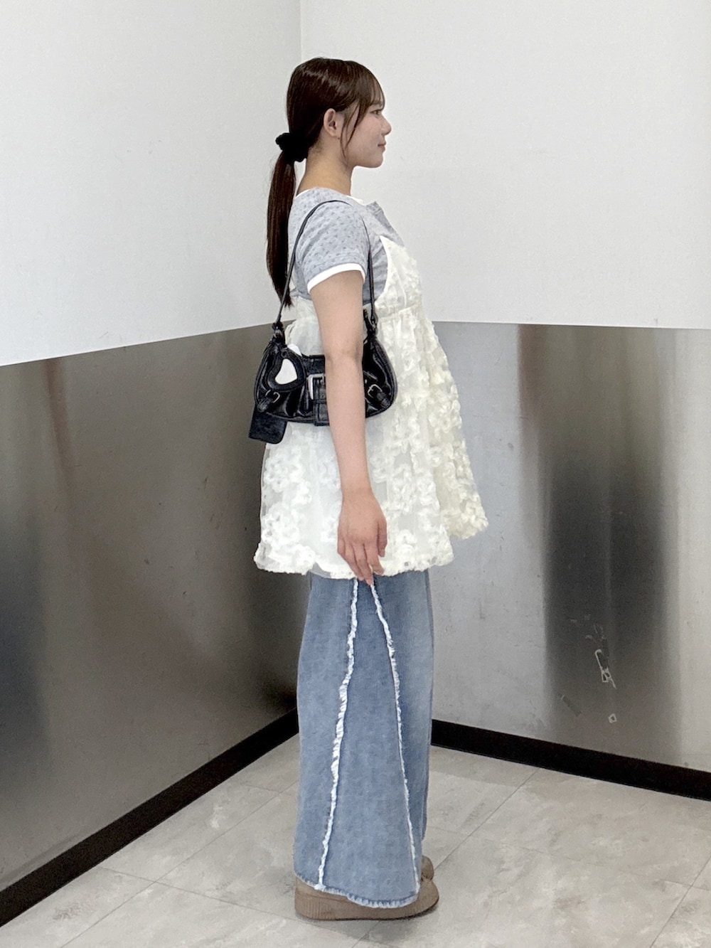 ホワイト系のチュニック、グレー系のTシャツ/カットソー、ブルー系のデニムパンツを着用したレディースの夏コーディネートの2枚目の写真