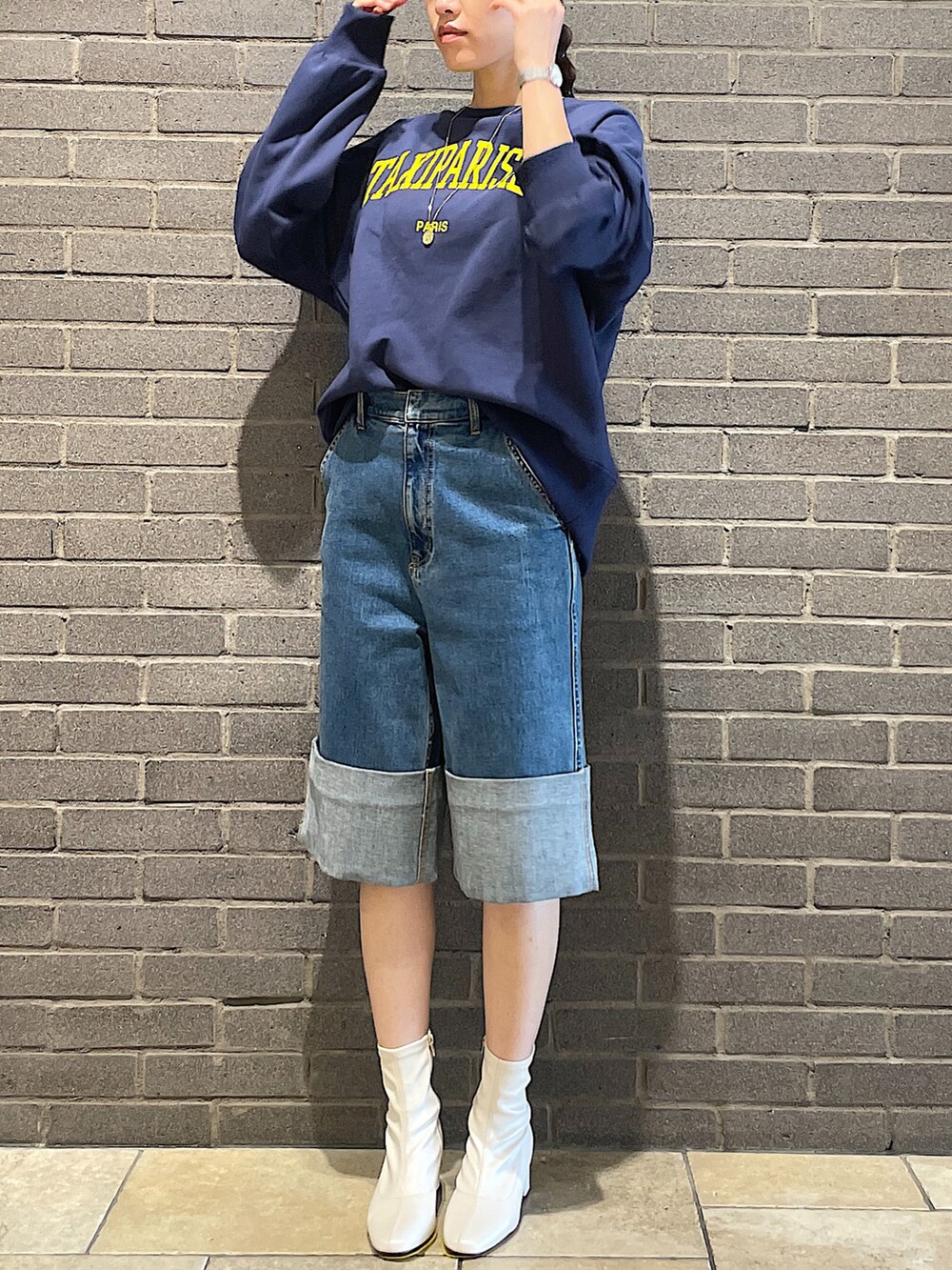 ブルー系のスウェット、ブルー系のデニムパンツ、ホワイト系のブーツを着用したレディースの夏コーディネートの5枚目の写真