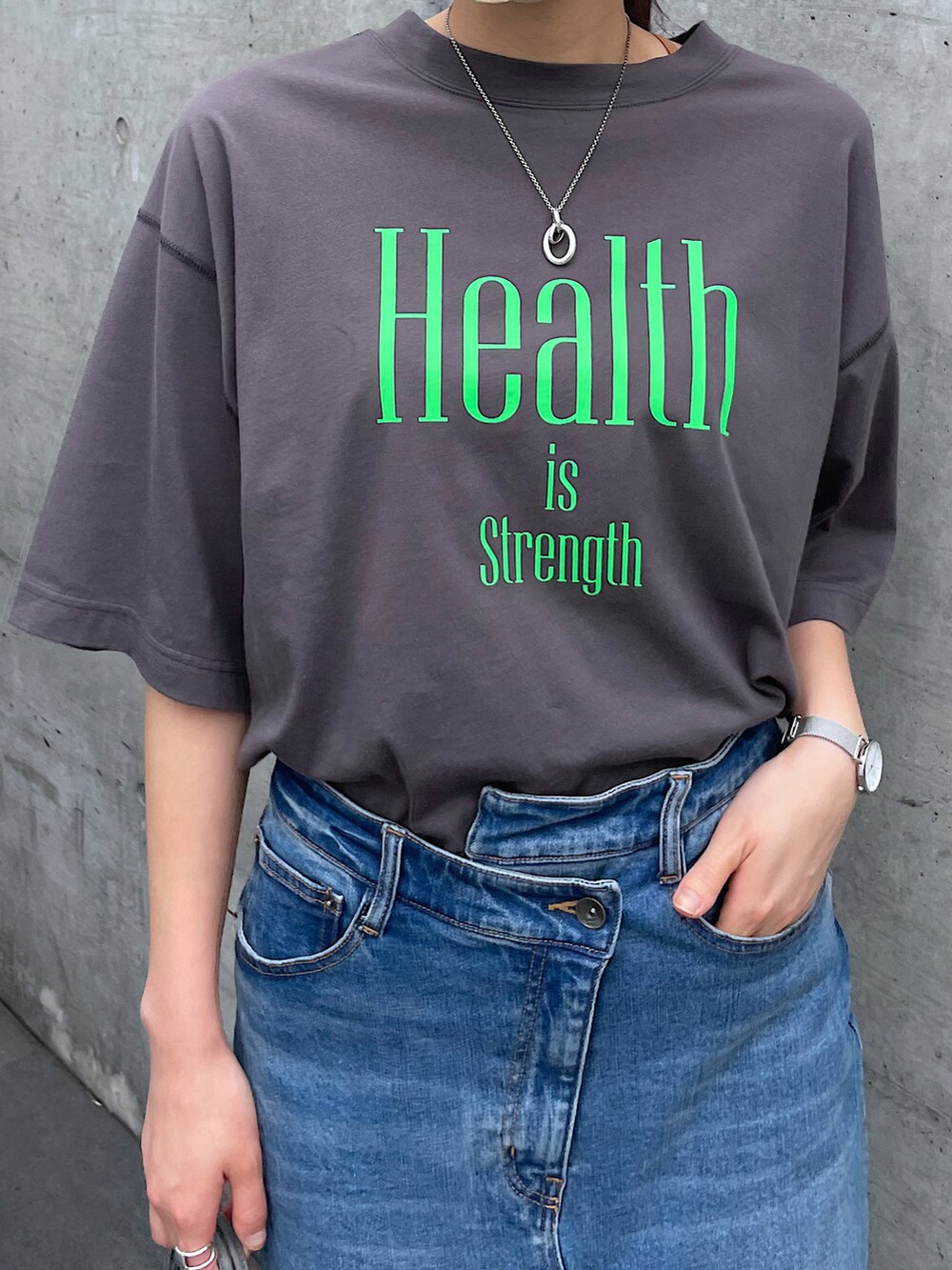 グレー系のTシャツ/カットソー、ブルー系のデニムスカート、グリーン系のショルダーバッグを着用したレディースの夏コーディネートの4枚目の写真