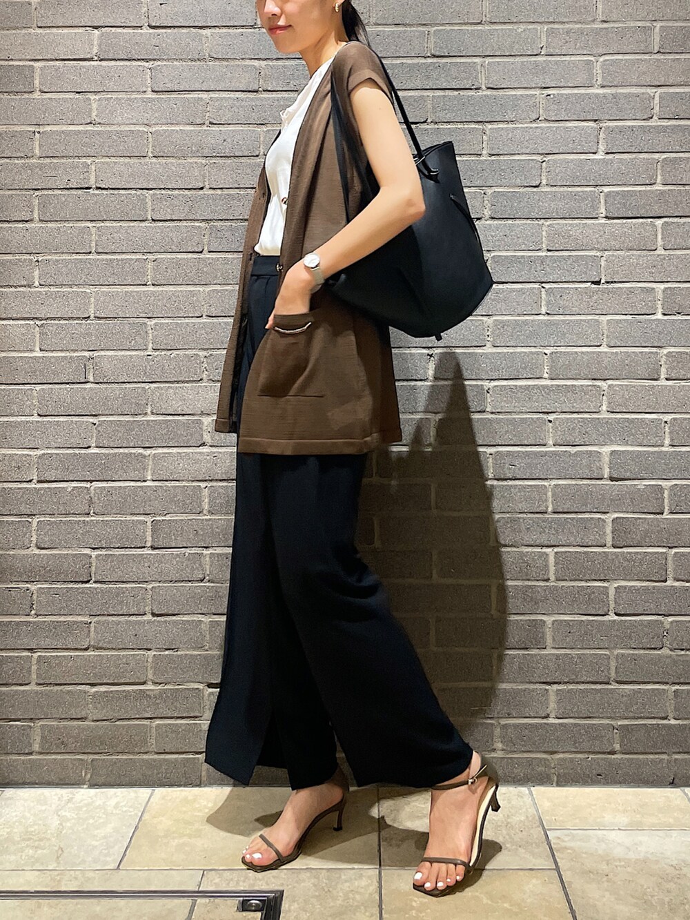 ホワイト系のタンクトップ、グリーン系のベスト、ブラック系のスラックスを着用したレディースの夏コーディネートの4枚目の写真