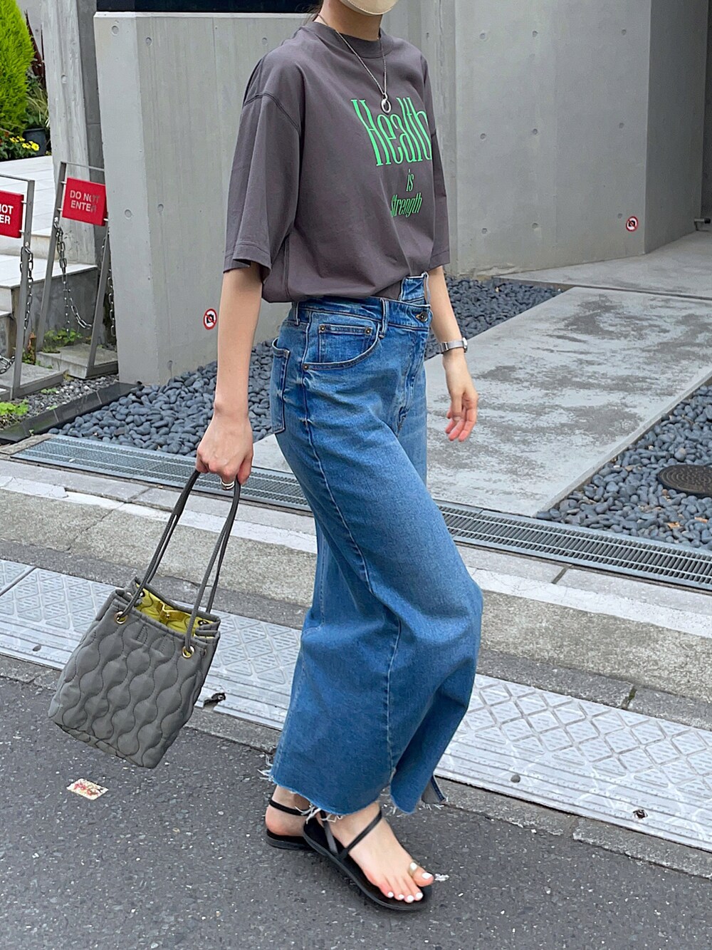 グレー系のTシャツ/カットソー、ブルー系のデニムスカート、グリーン系のショルダーバッグを着用したレディースの夏コーディネートの3枚目の写真